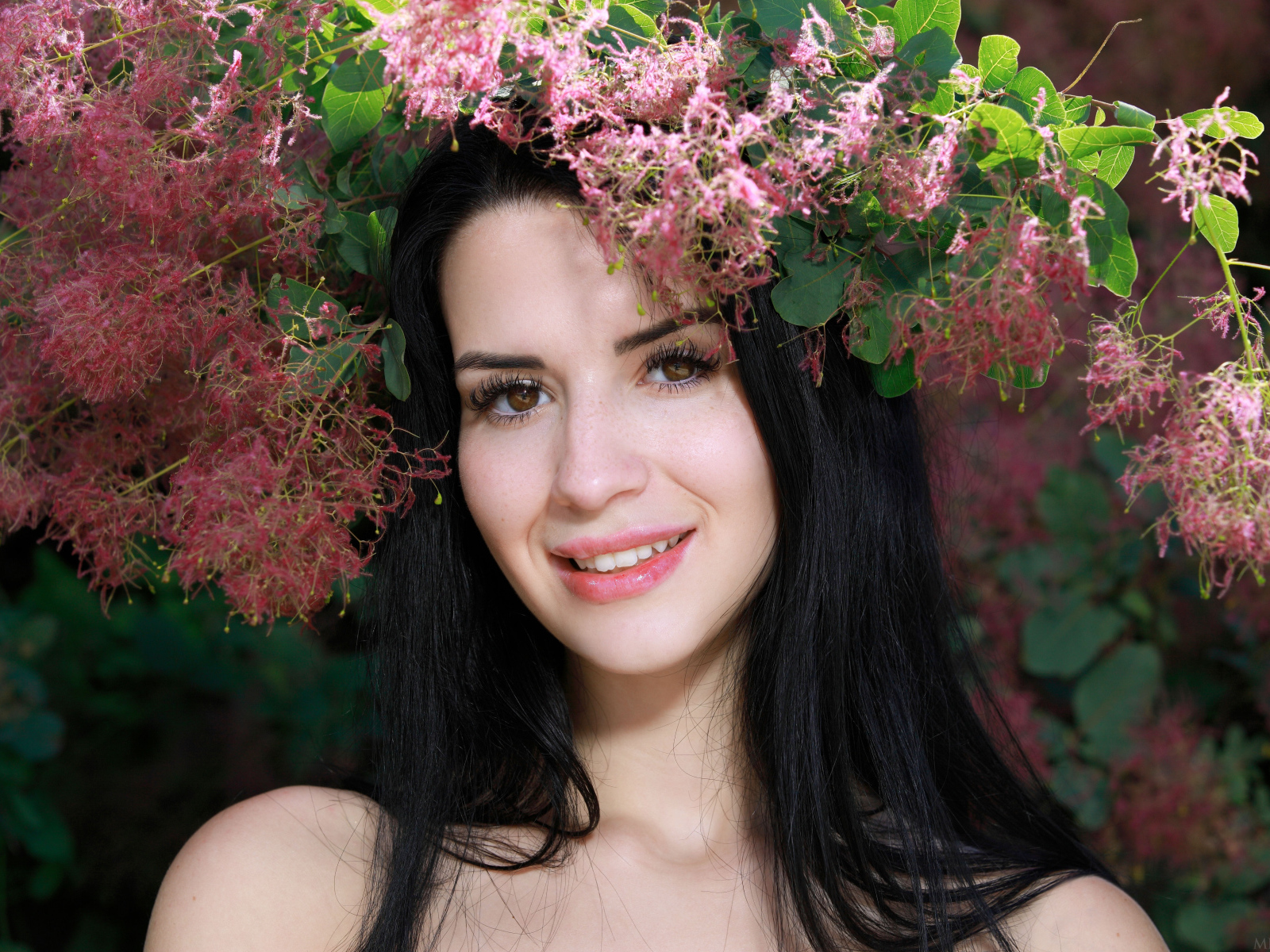 Красивая брюнетка стоит у цветущей ветки