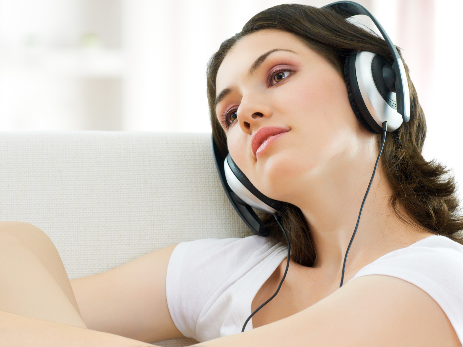 Красивая нежная шатенка слушает музыку в наушниках