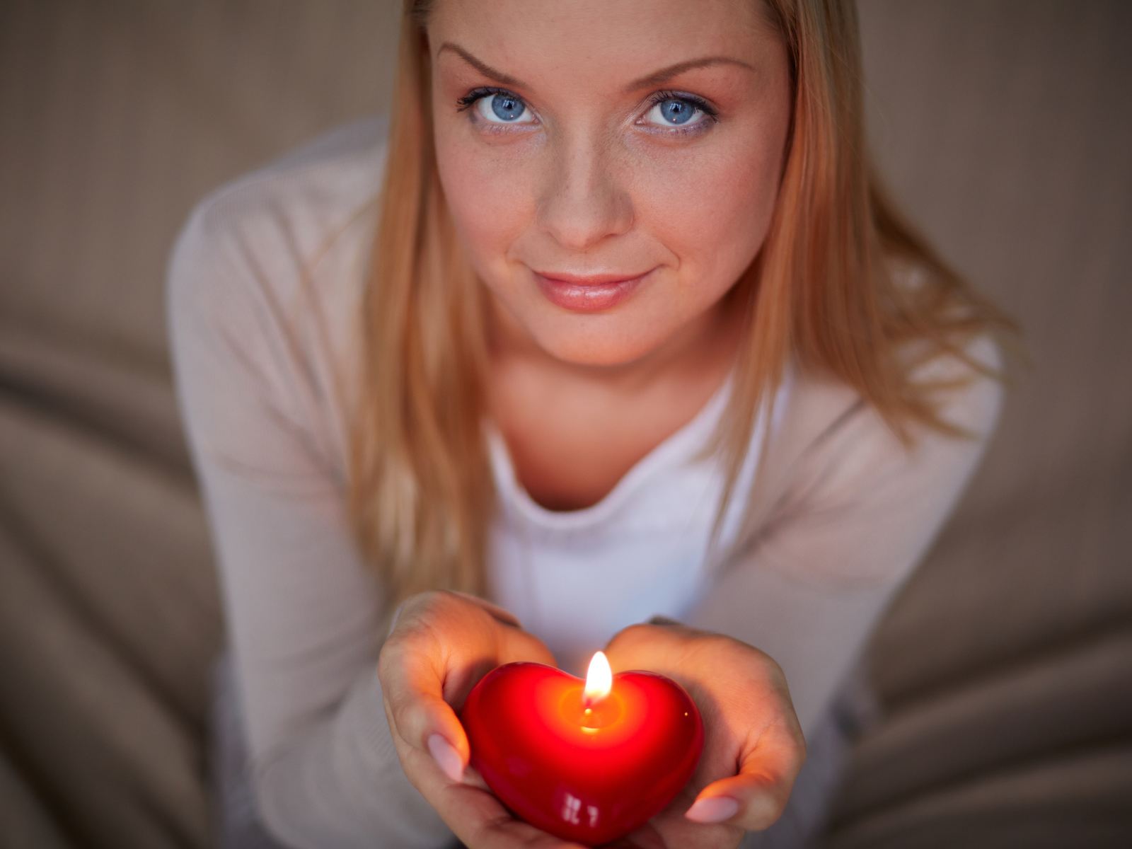 Красивая девушка держит в руках свечу в форме сердца