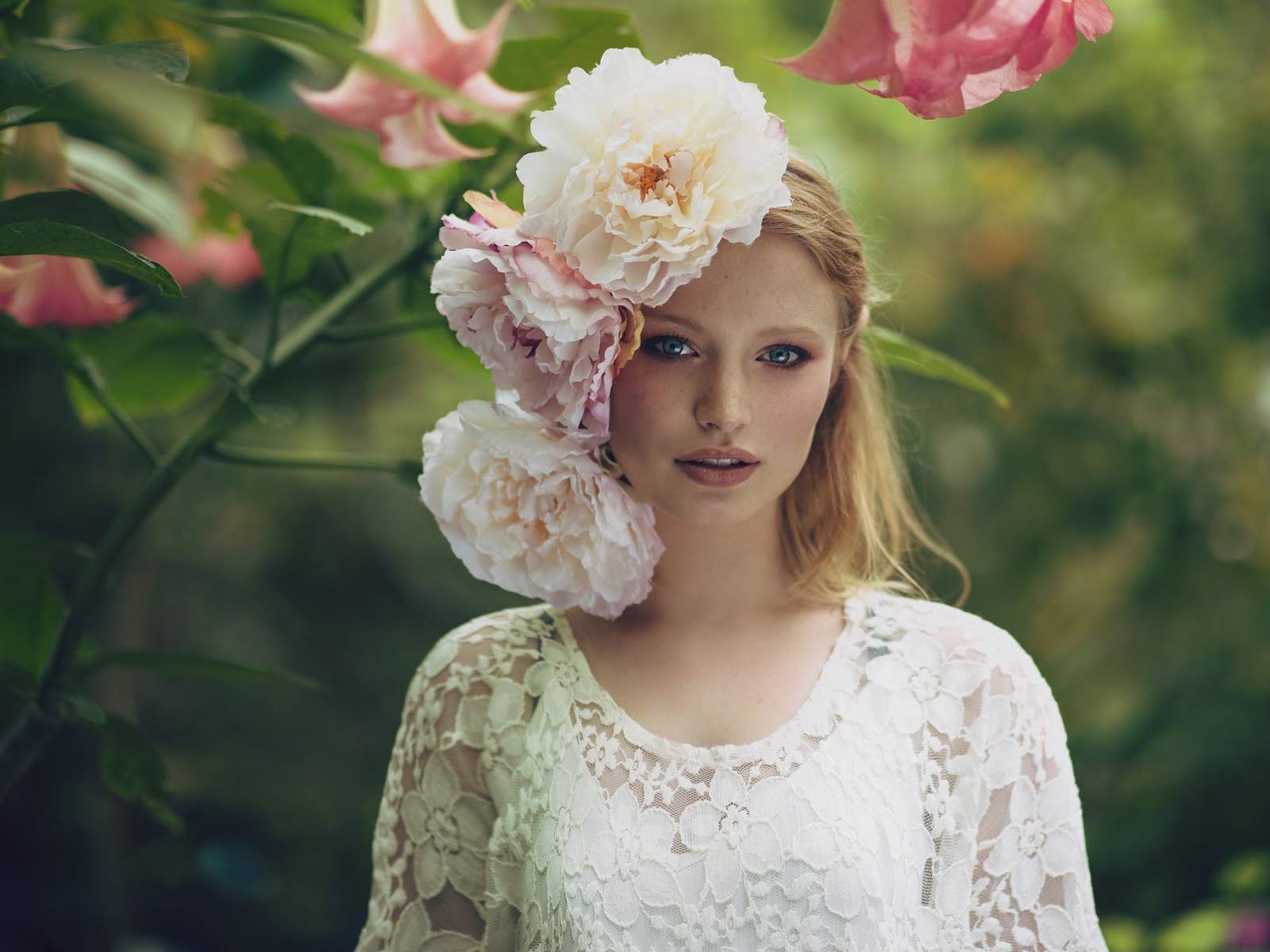 Красивая девушка в белом платье с большими пионами в волосах 