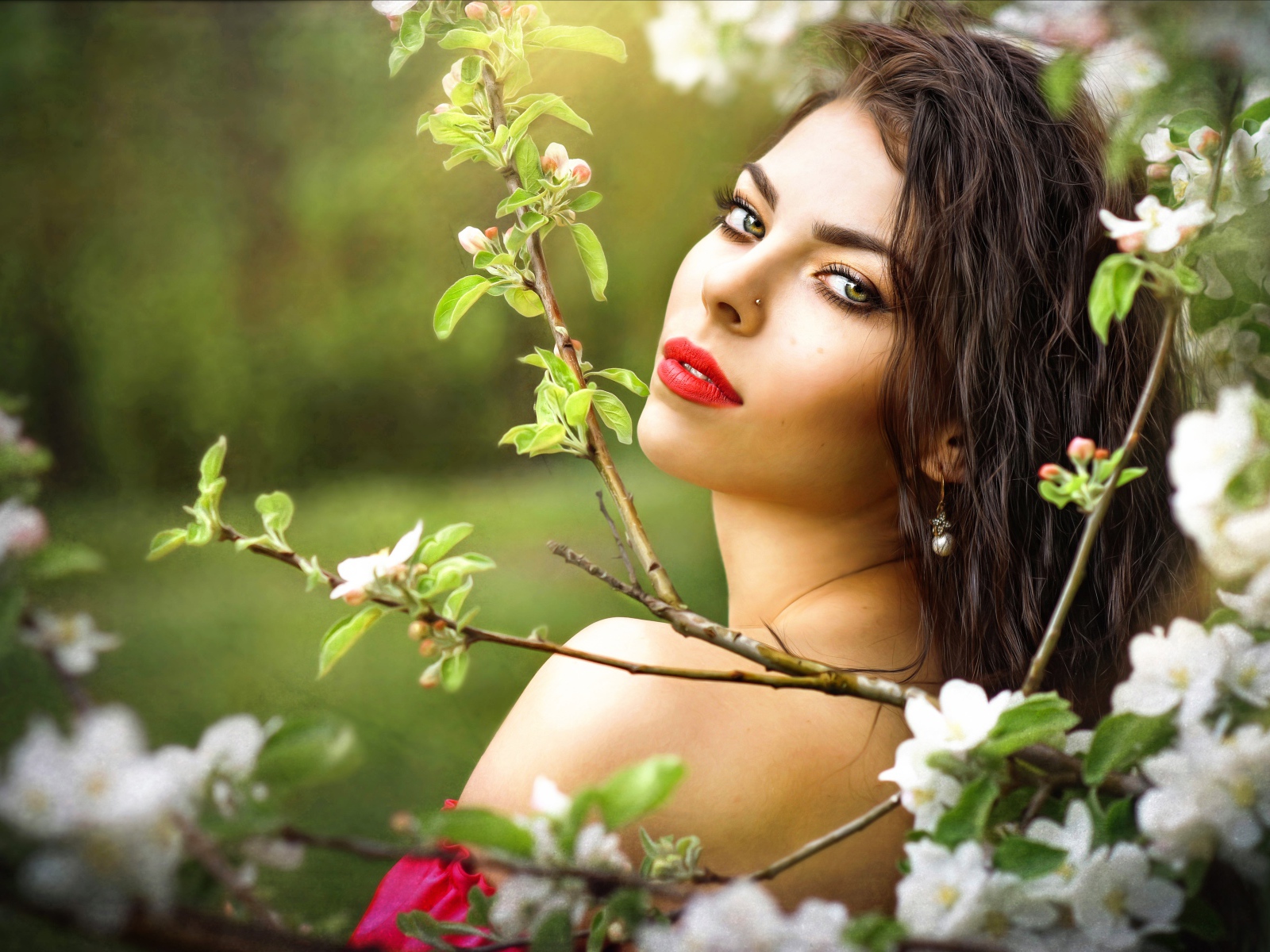 Красивая молодая девушка в ветках цветущей яблони 