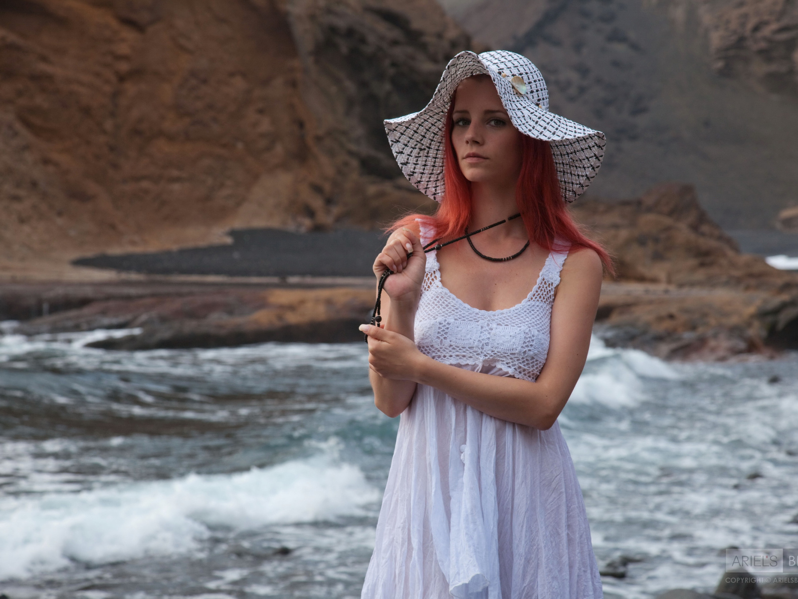 Рыжеволосая девушка в шляпе и белом платье у реки