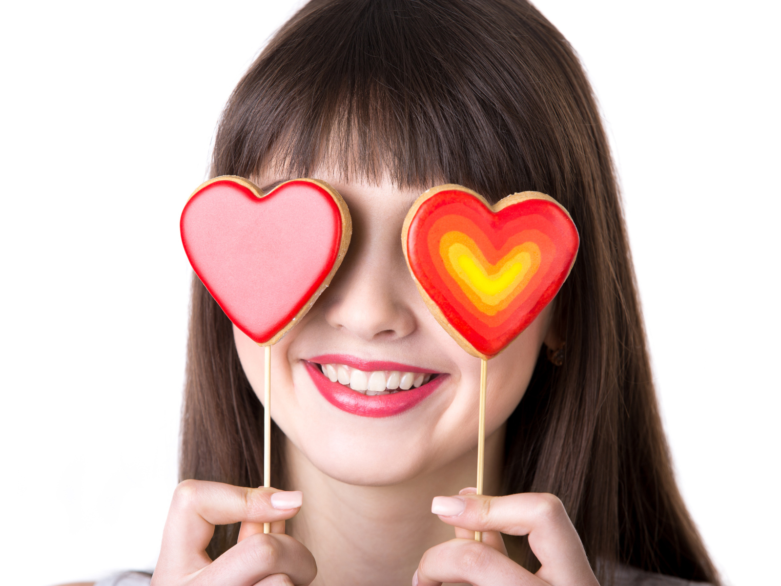 Красивая девушка шатенка закрыла глаза леденцами в форме сердца