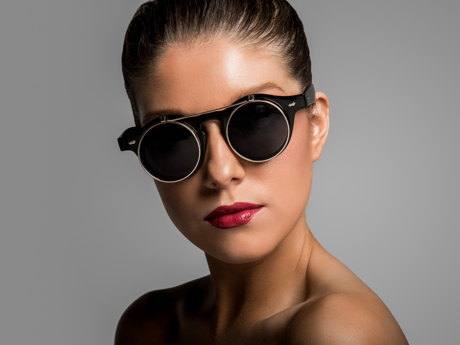 Лицо девушки в черных очках на сером фоне
