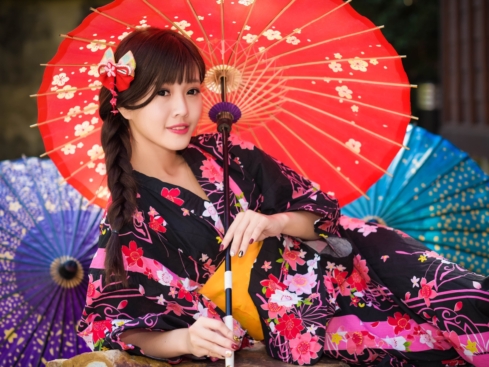 Молодая азиатка в кимоно с разноцветными зонтиками
