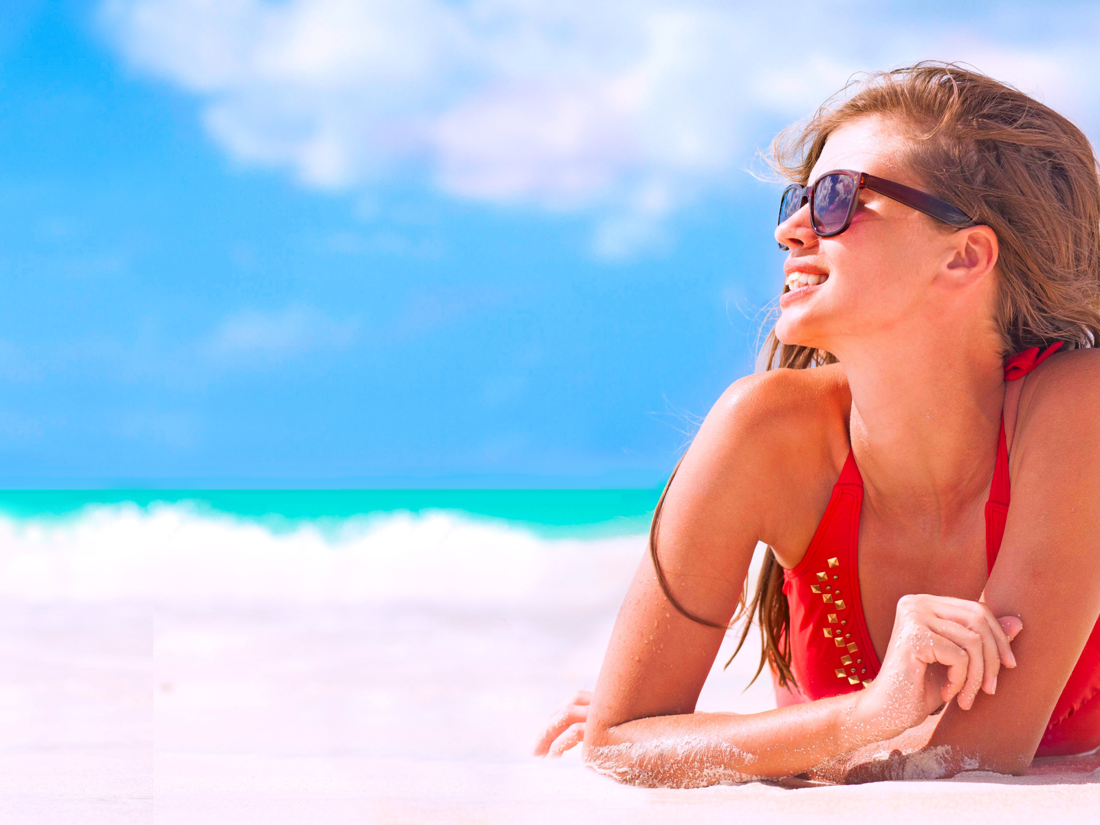 Молодая девушка в очках загорает на пляже