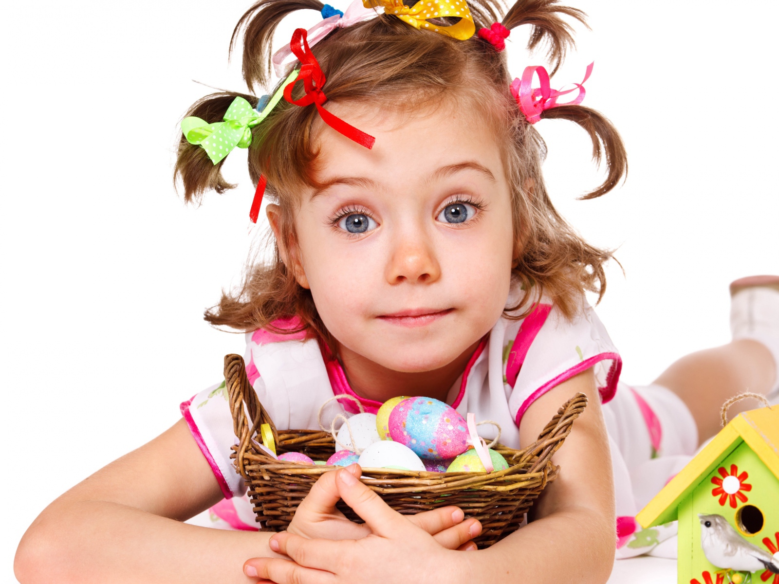 Маленькая девочка с корзинкой пасхальных яиц на белом фоне 