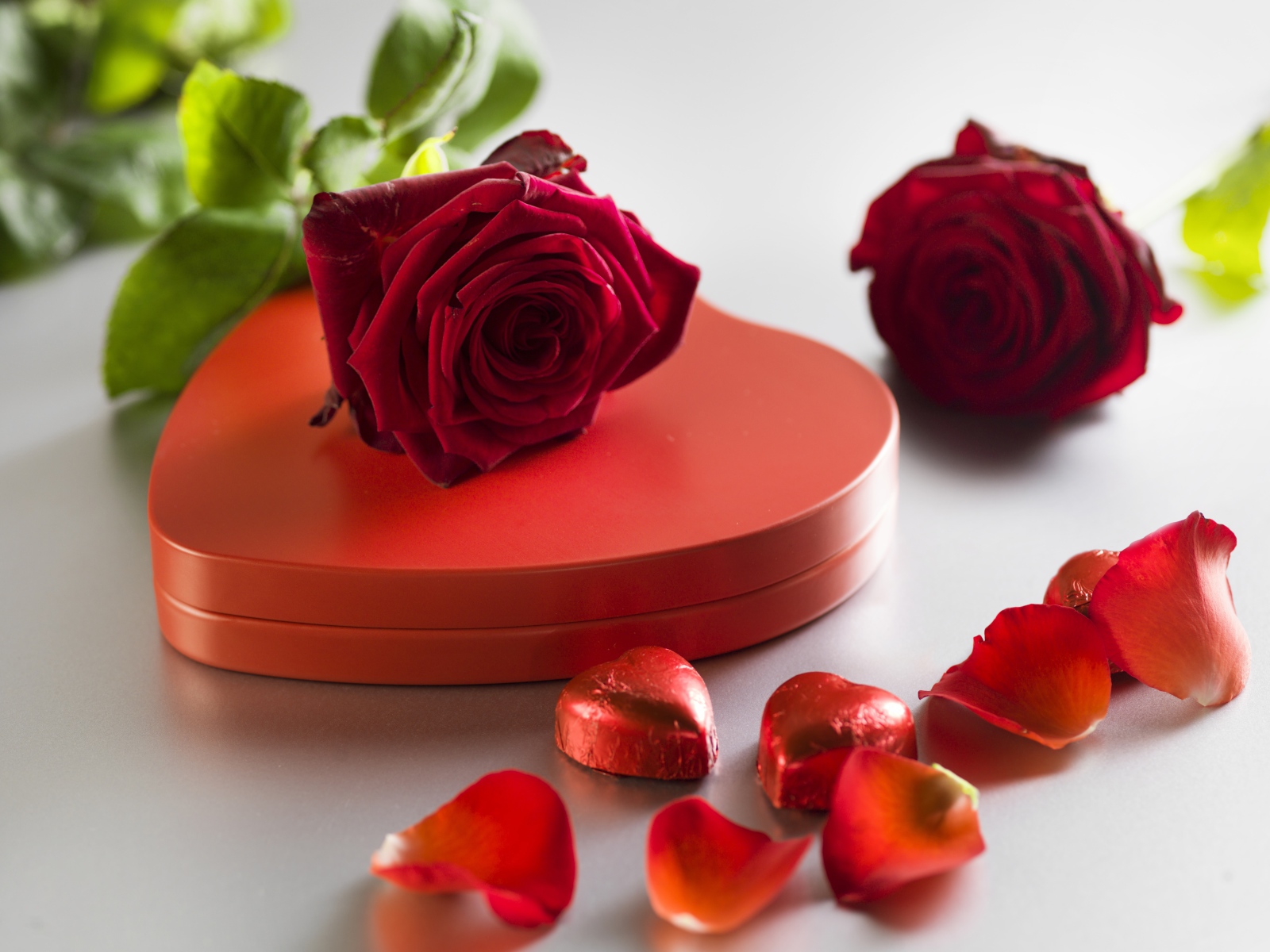 Большая красная коробка в форме сердца с шоколадными конфетами и красными розами