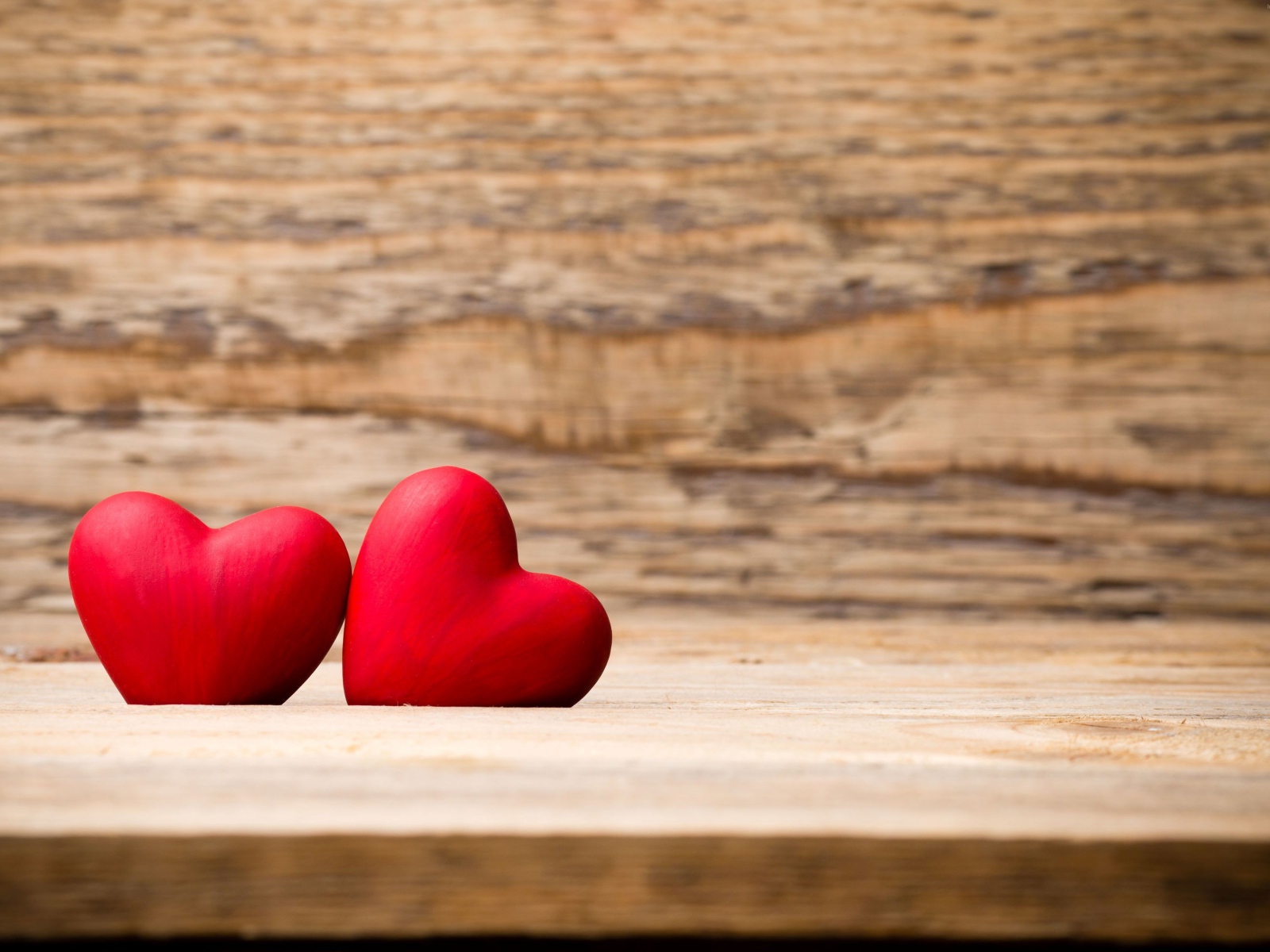 Два красных сердца лежат на деревянной лавке