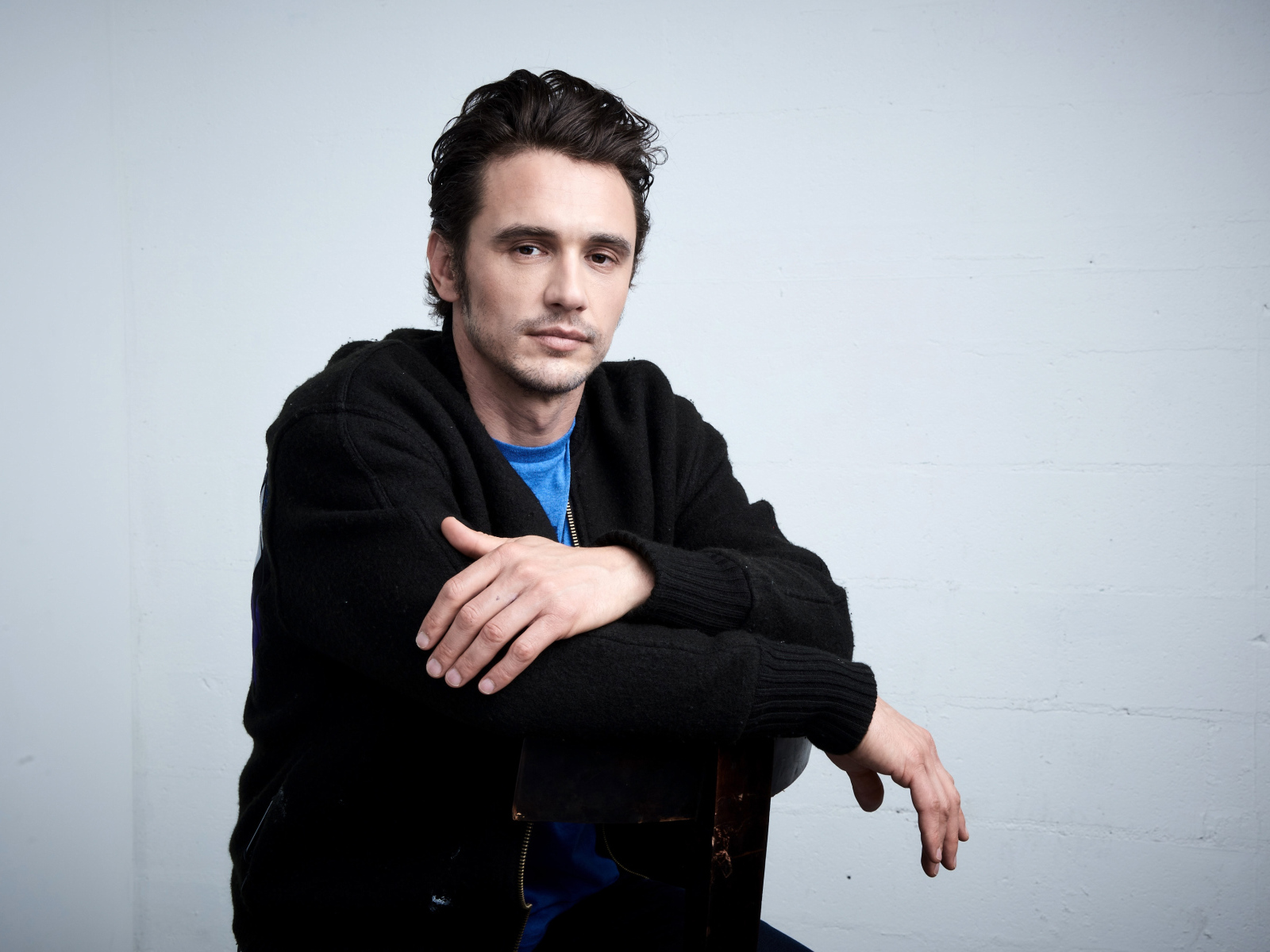 Актер Джеймс Франко в черной кофте на сером фоне