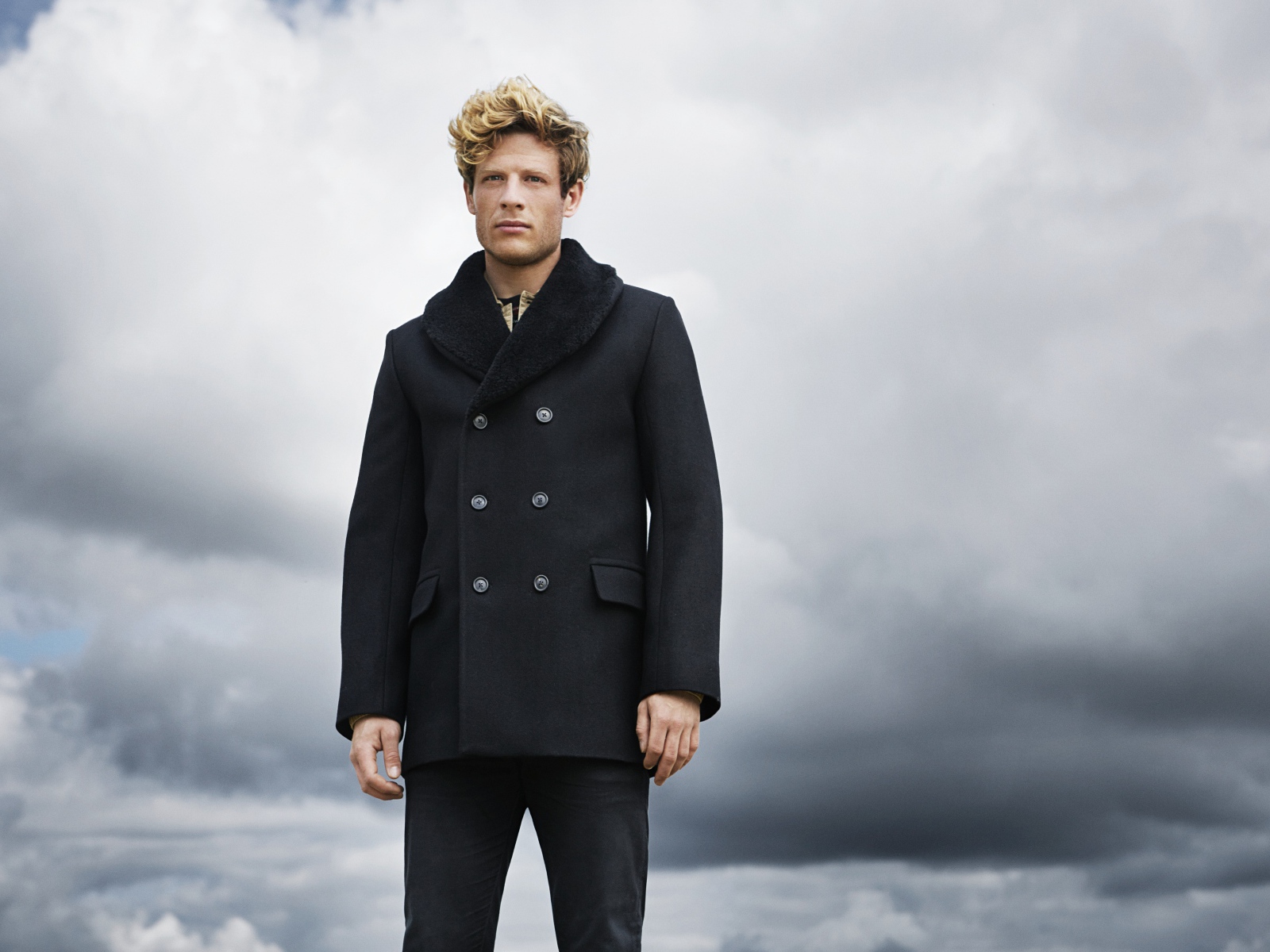 Актер Джеймс Нортон в черном пальто на фоне неба