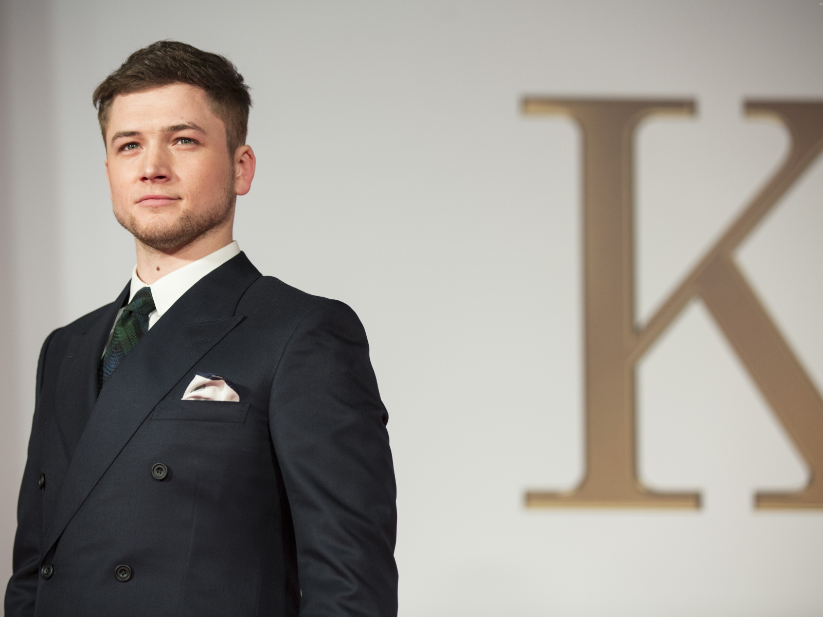 Молодой актер Терон Эгертон в черном пиджаке