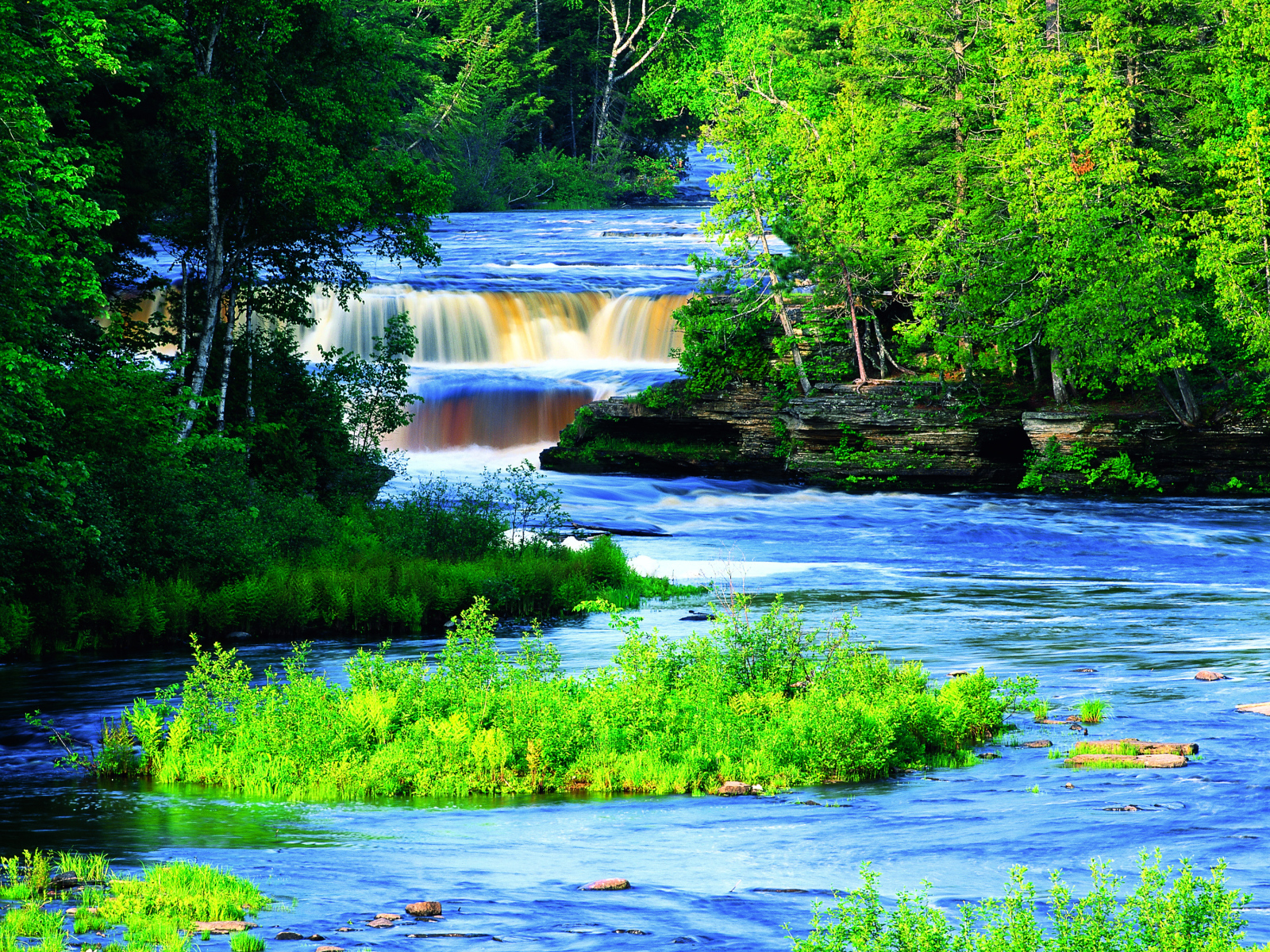 A picturesque river with a waterfall between green trees