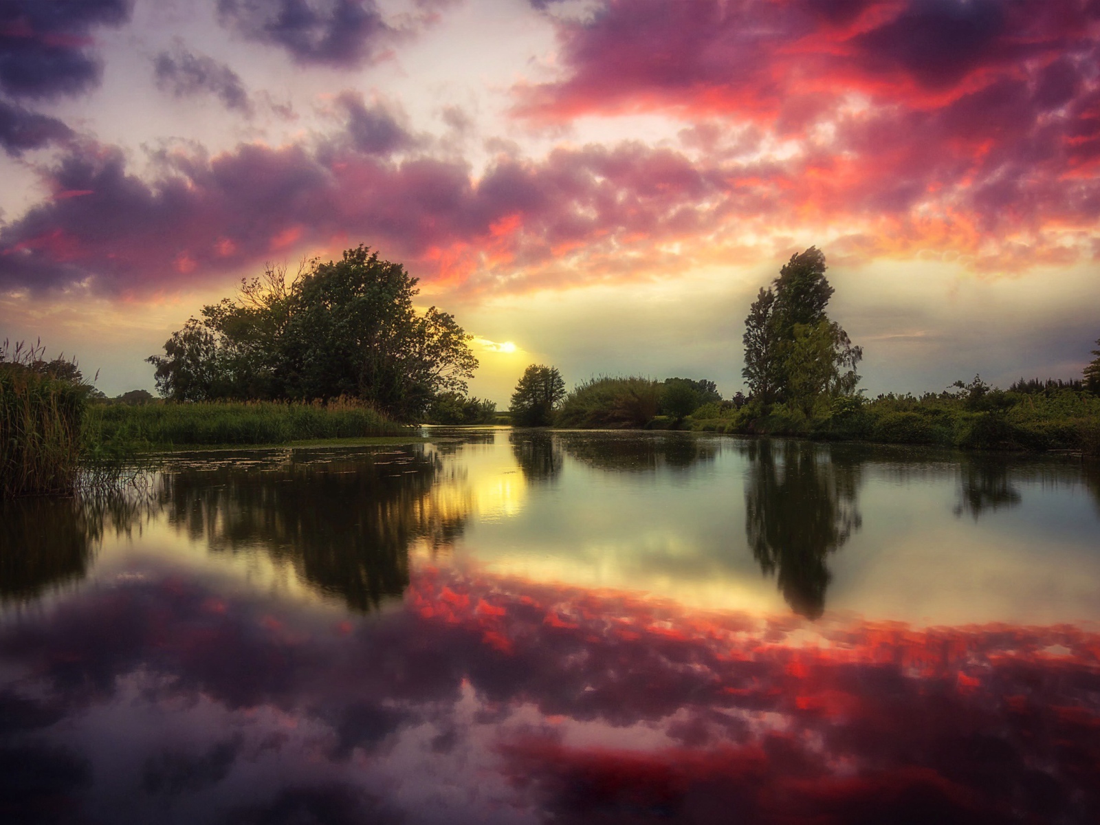Красные облака отражаются в чистой воде реки