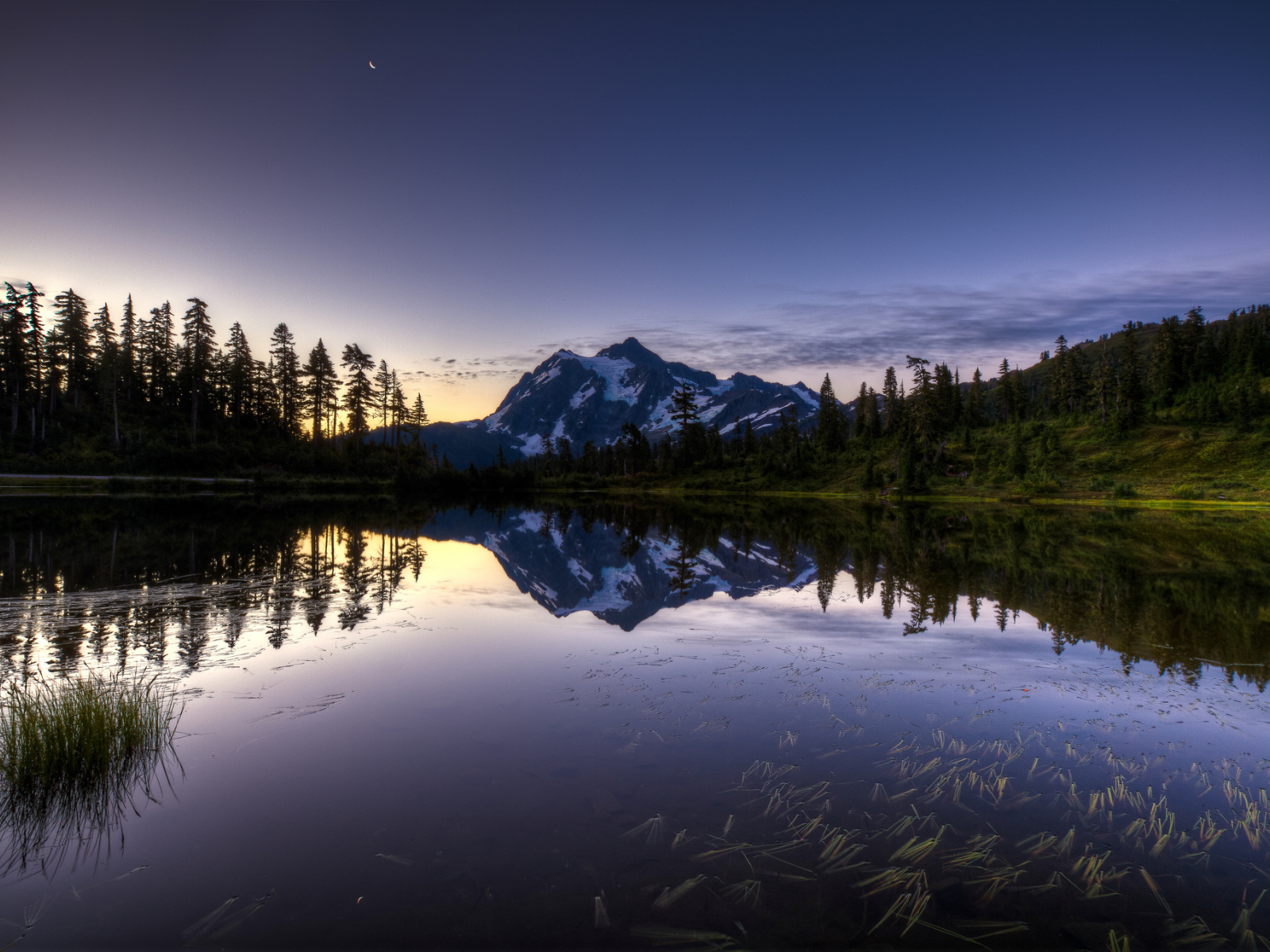 Заснеженная гора и лес отражается в озере вечером
