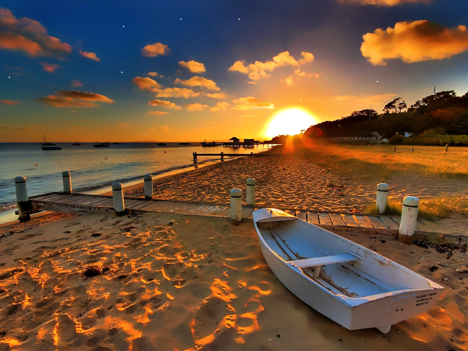 Белая лодка на пляже под закатным солнцем