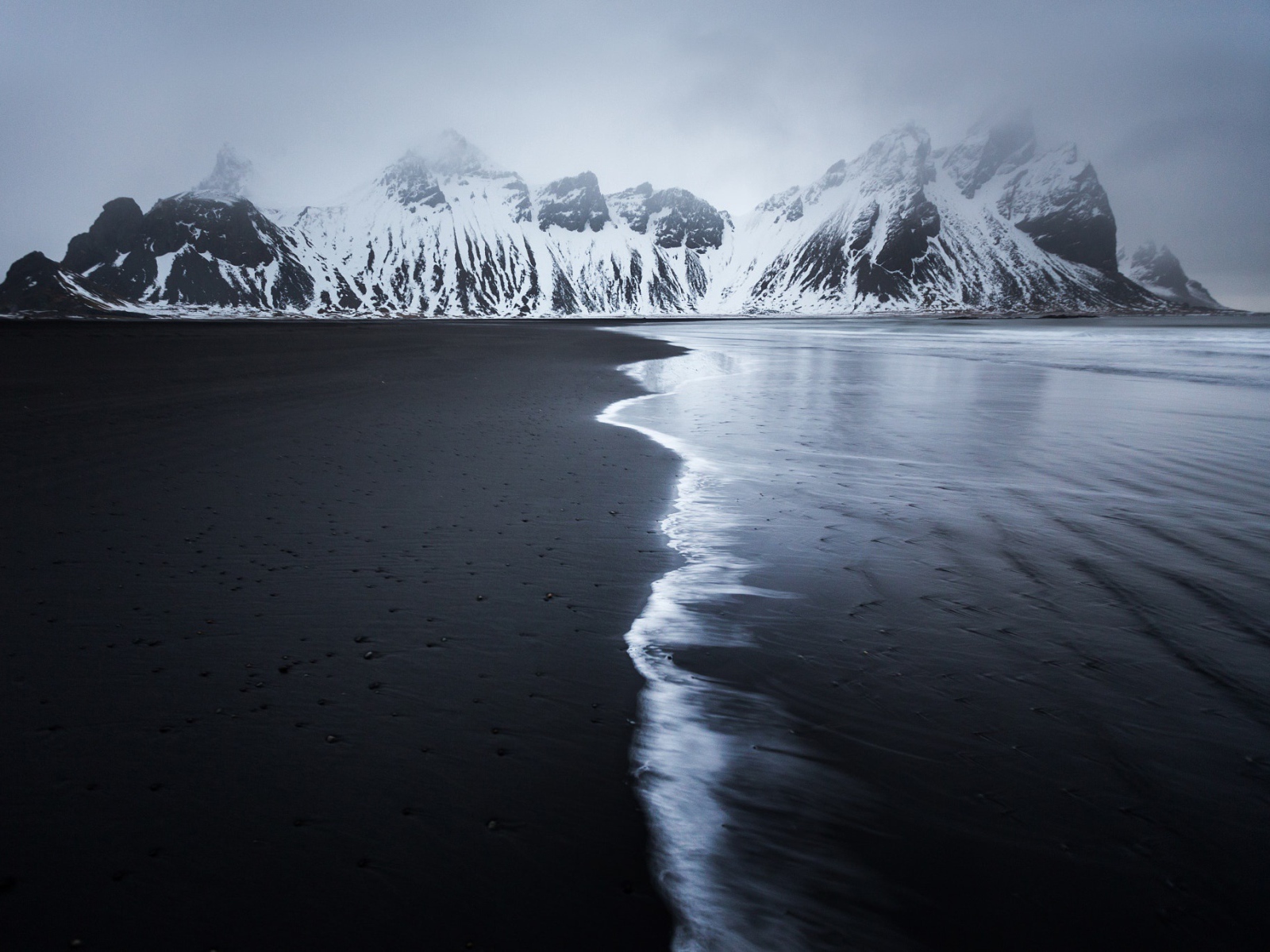 Заснеженные горы у пустынного пляжа