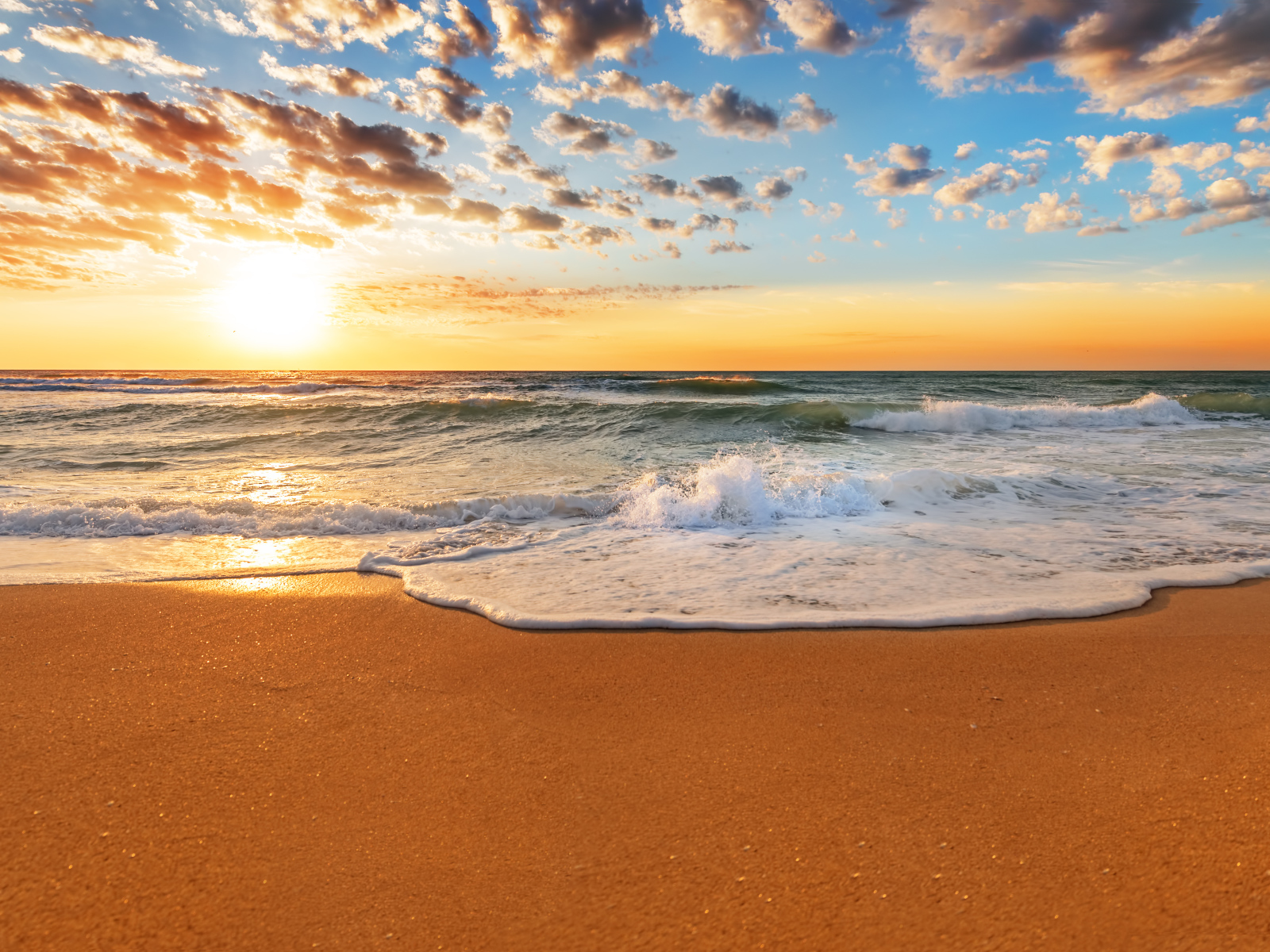 Волна омывает горячий желтый песок на берегу моря