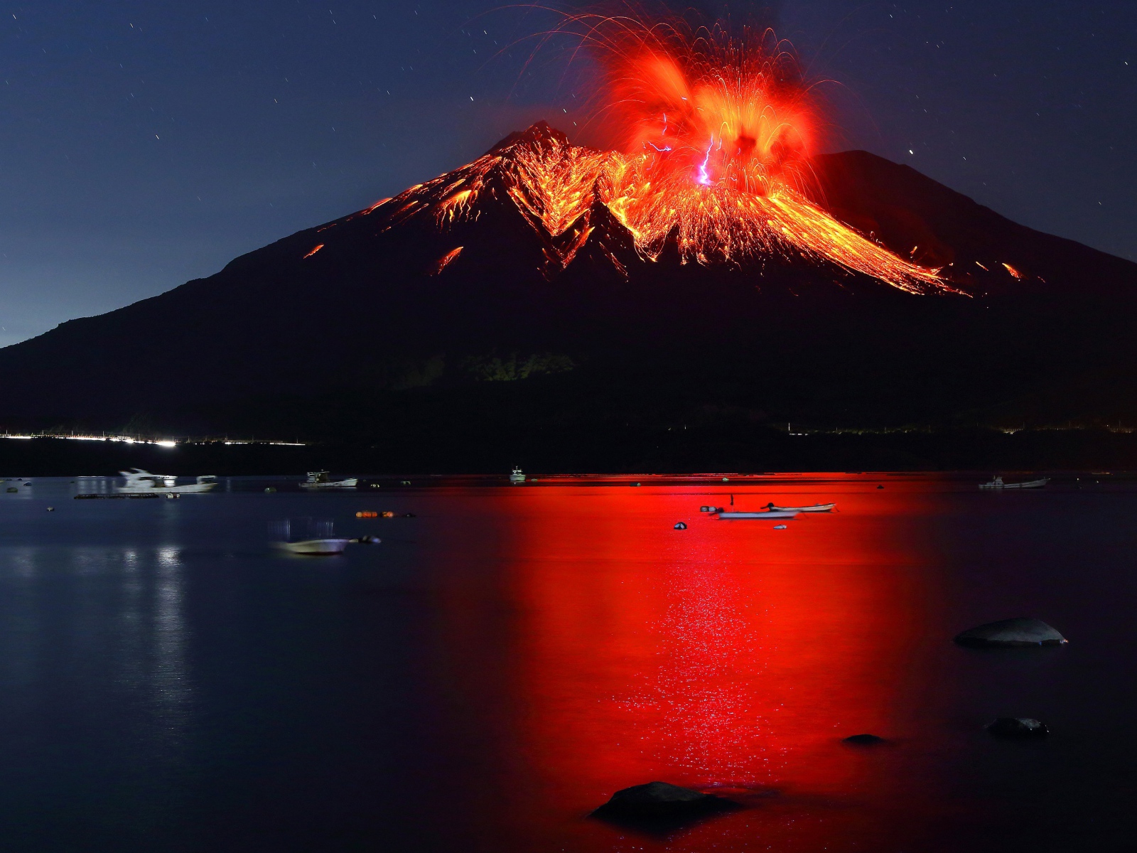 Вулкан Сакурадзима извергается  на фоне воды 