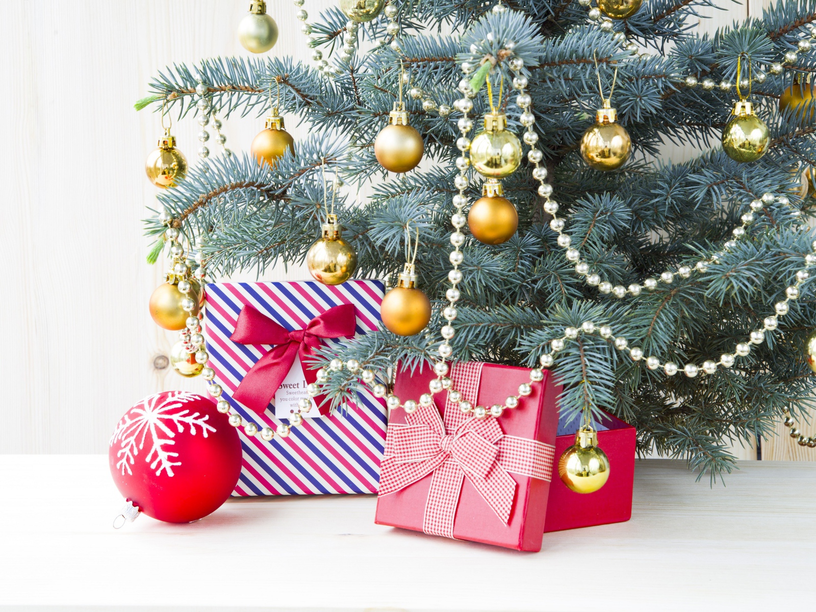 Подарки под зеленой наряженной елкой с золотыми шарами