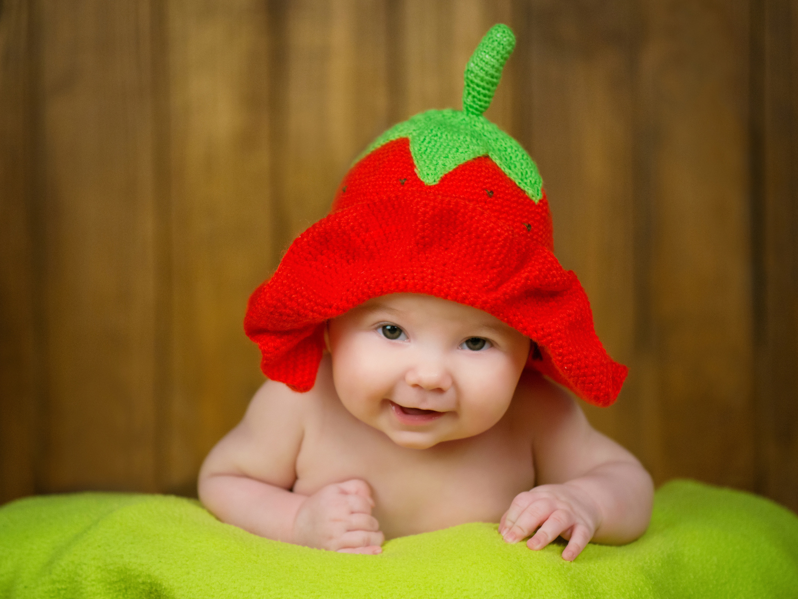 Младенец в забавной шапке клубнике на голове