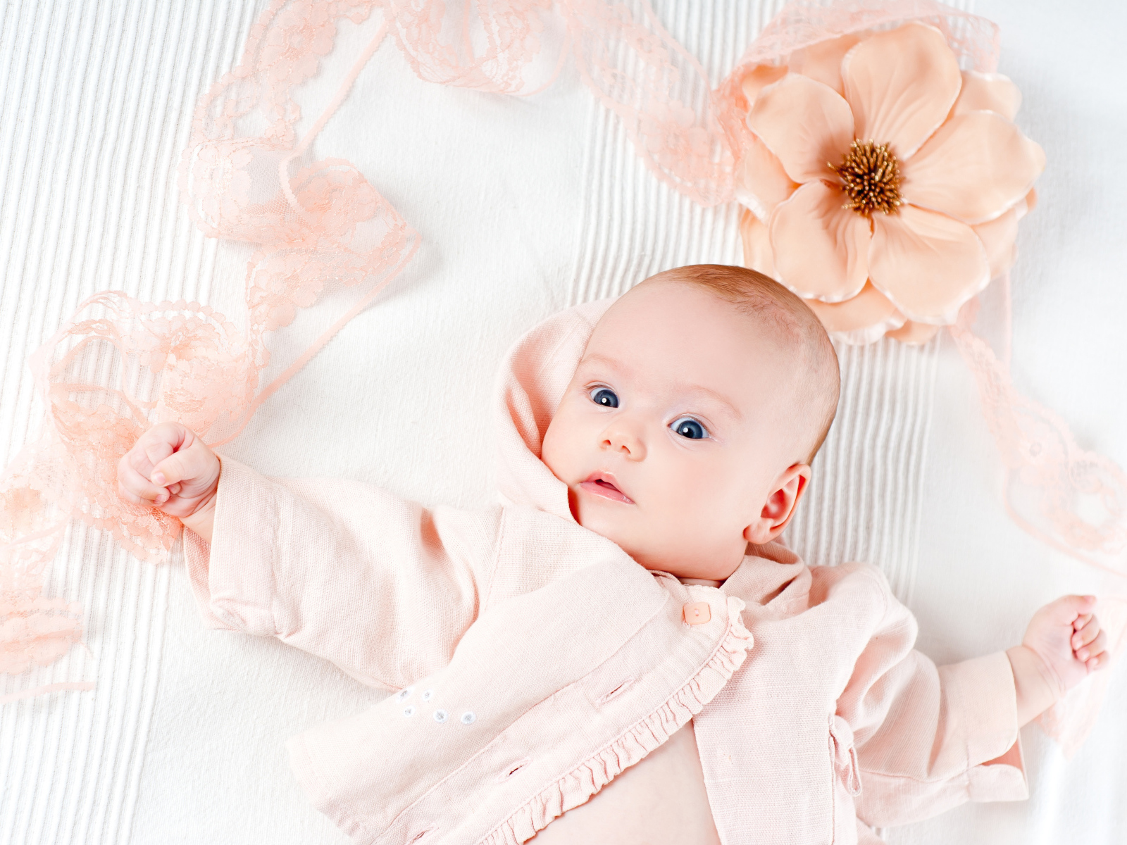 Младенец в розовом наряде с большим цветком у головы