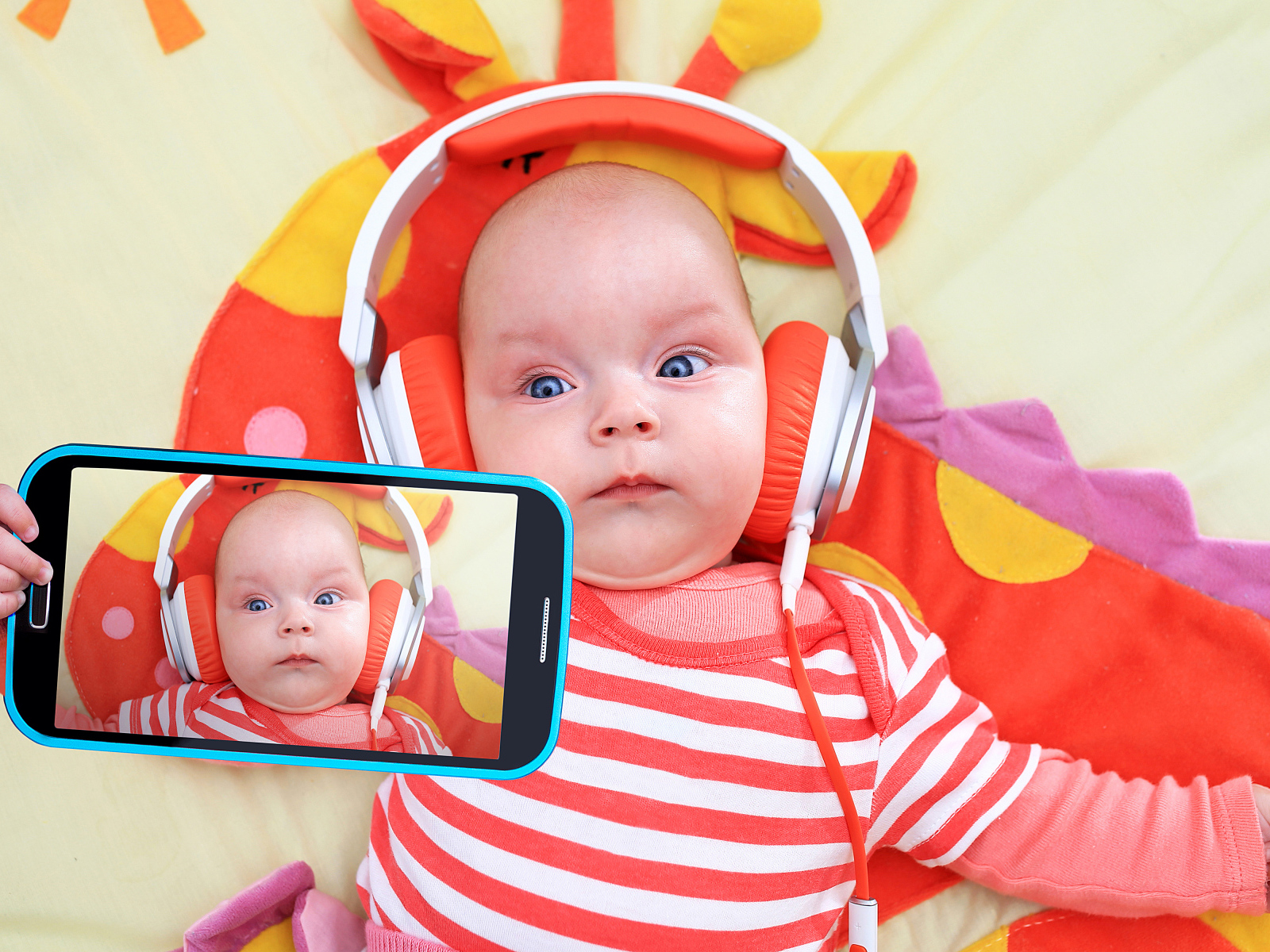 Младенец в оранжевых наушниках делает селфи