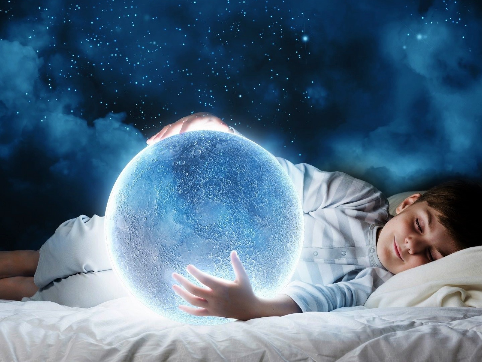 Маленький мальчик во сне держит в руках волшебную голубую луну
