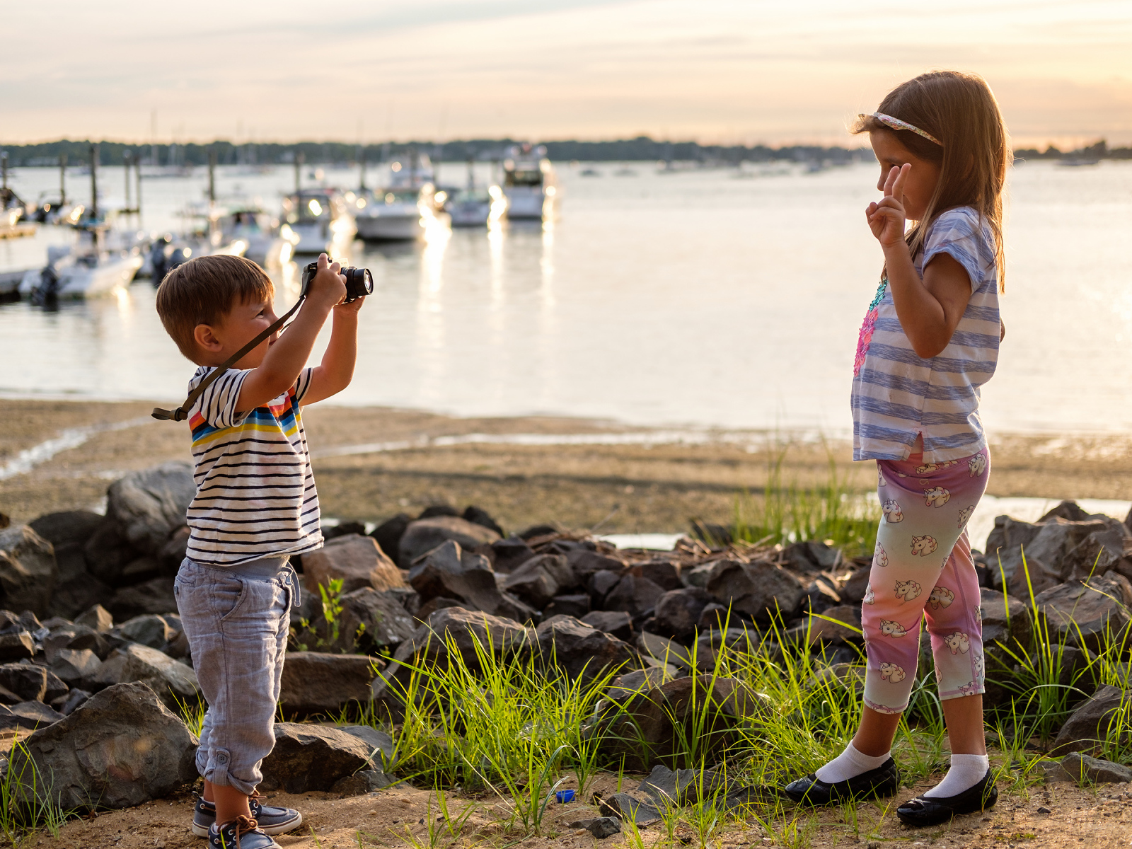 Маленький мальчик фотографирует девочку на берегу