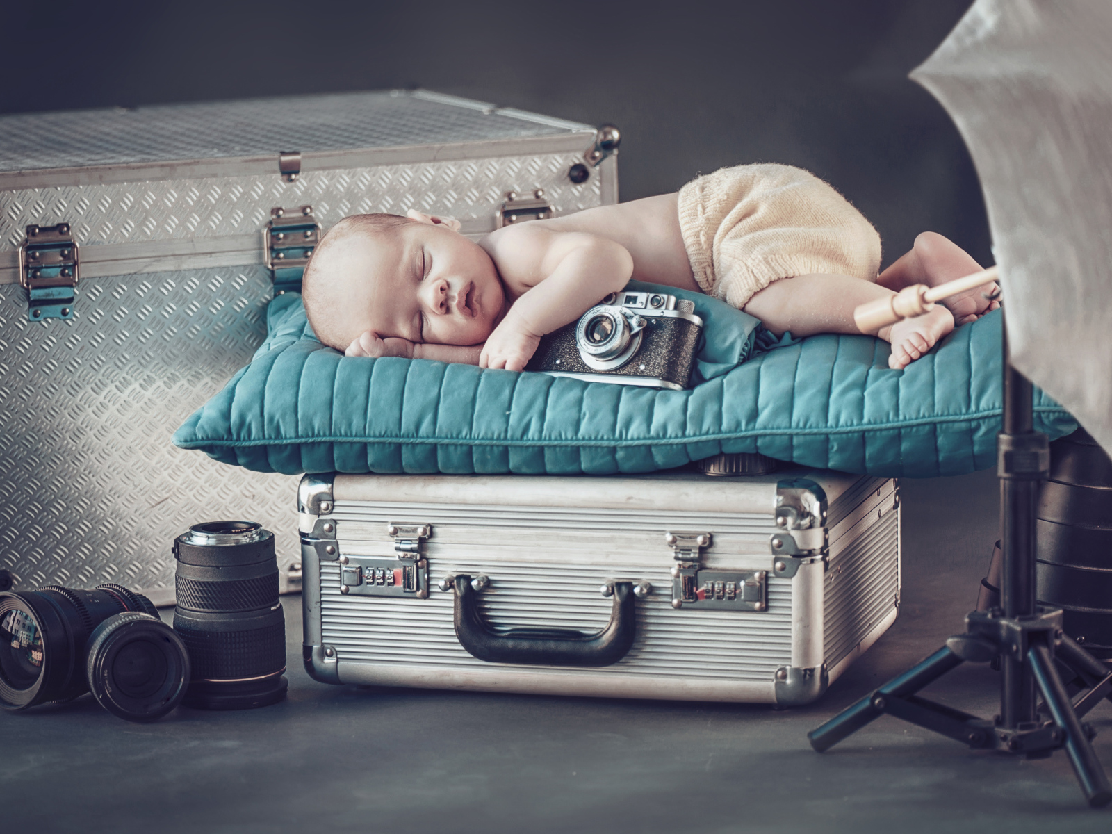 Спящий младенец с фотоаппаратом спит на чемодане