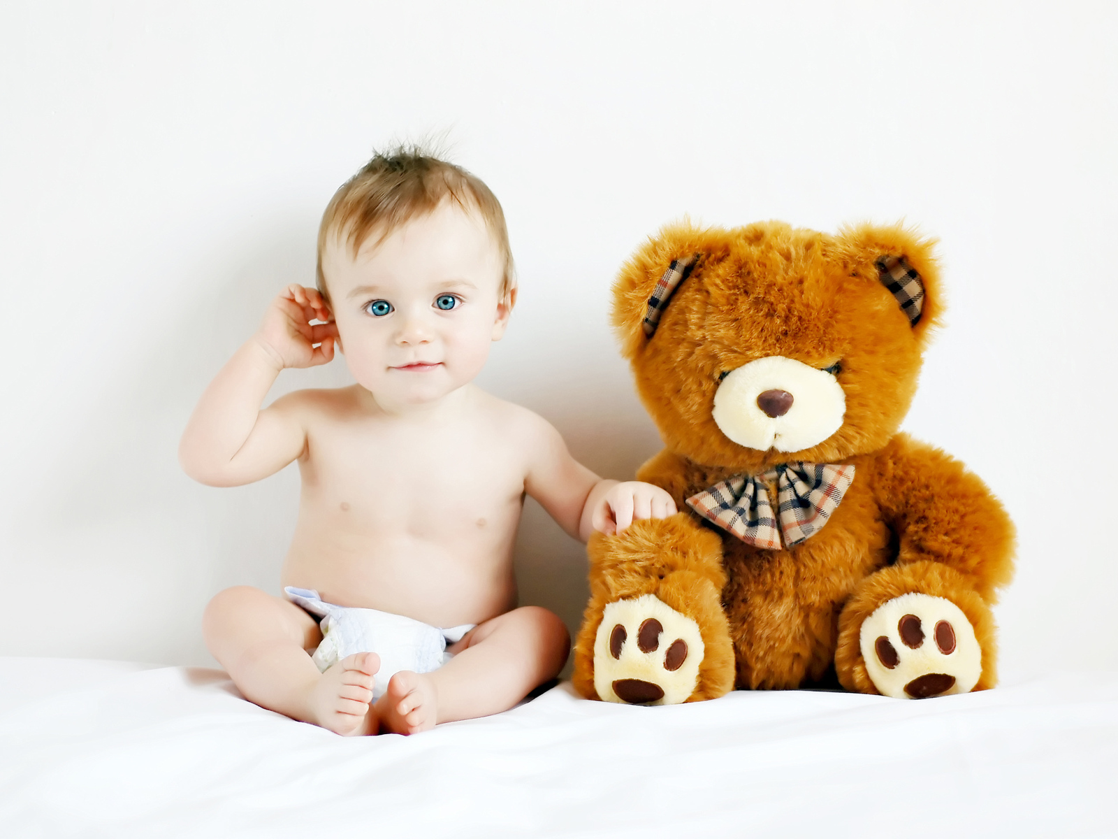 Маленький голубоглазый ребенок с большим плюшевым медведем