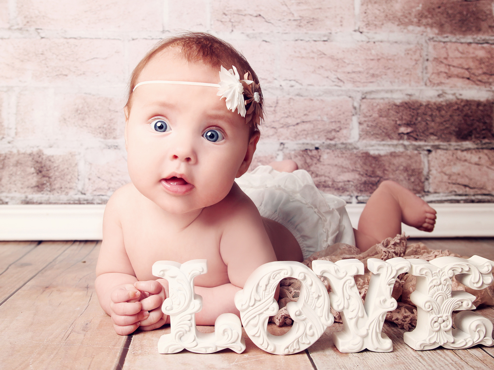 Грудной ребенок с надписью любовь на фоне кирпичной стены