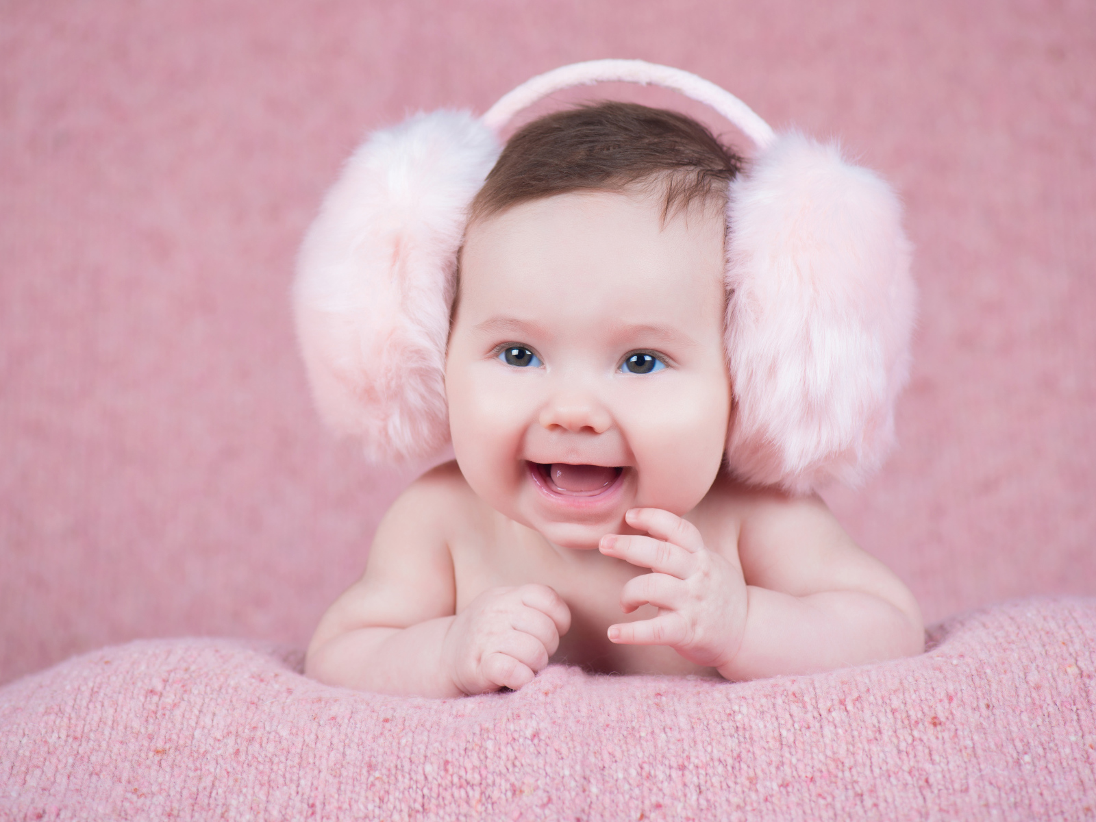 Милый улыбающийся младенец в больших розовых наушниках