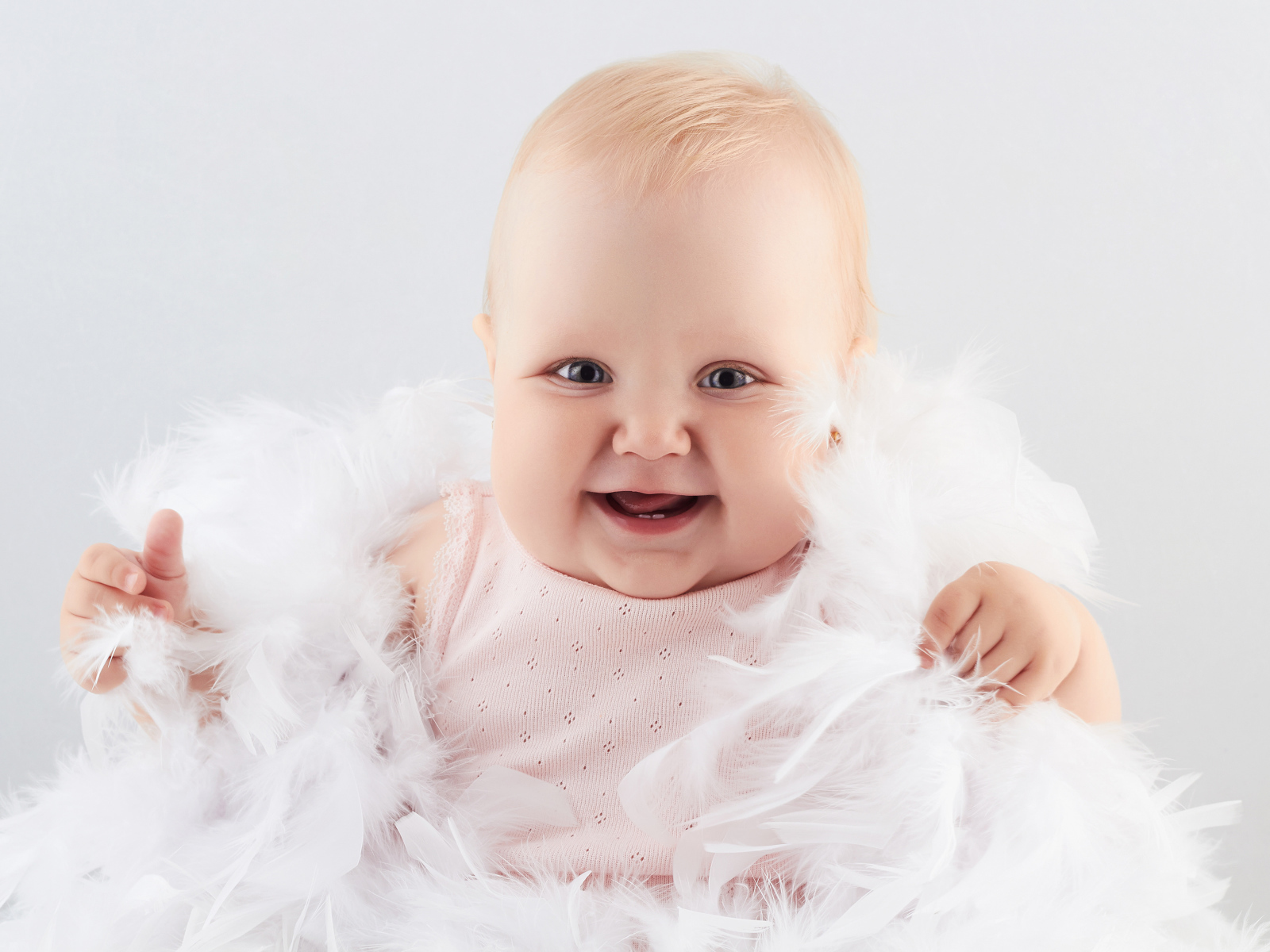 Забавная улыбающаяся маленькая девочка в белых перьях
