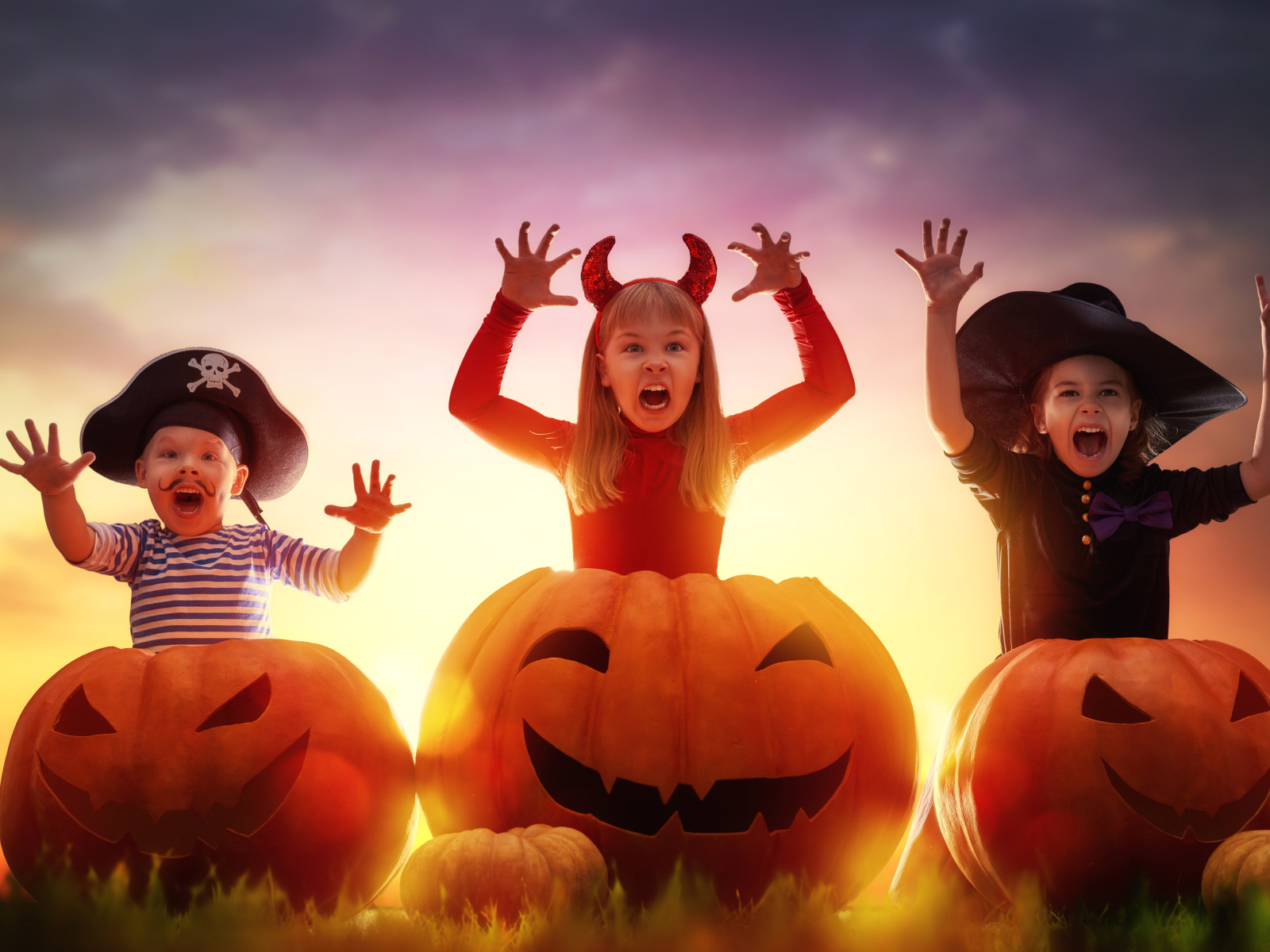 Маленькие дети в костюмах на Хэллоуин с большими тыквами