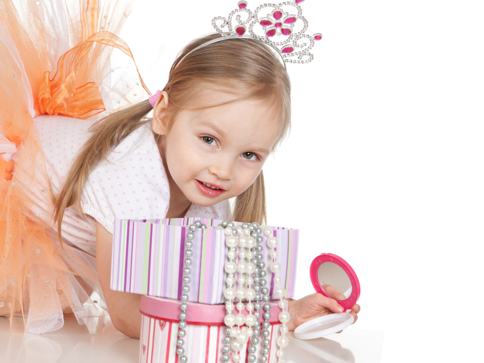 Маленькая девочка в короне на голове и с зеркалом на белом фоне