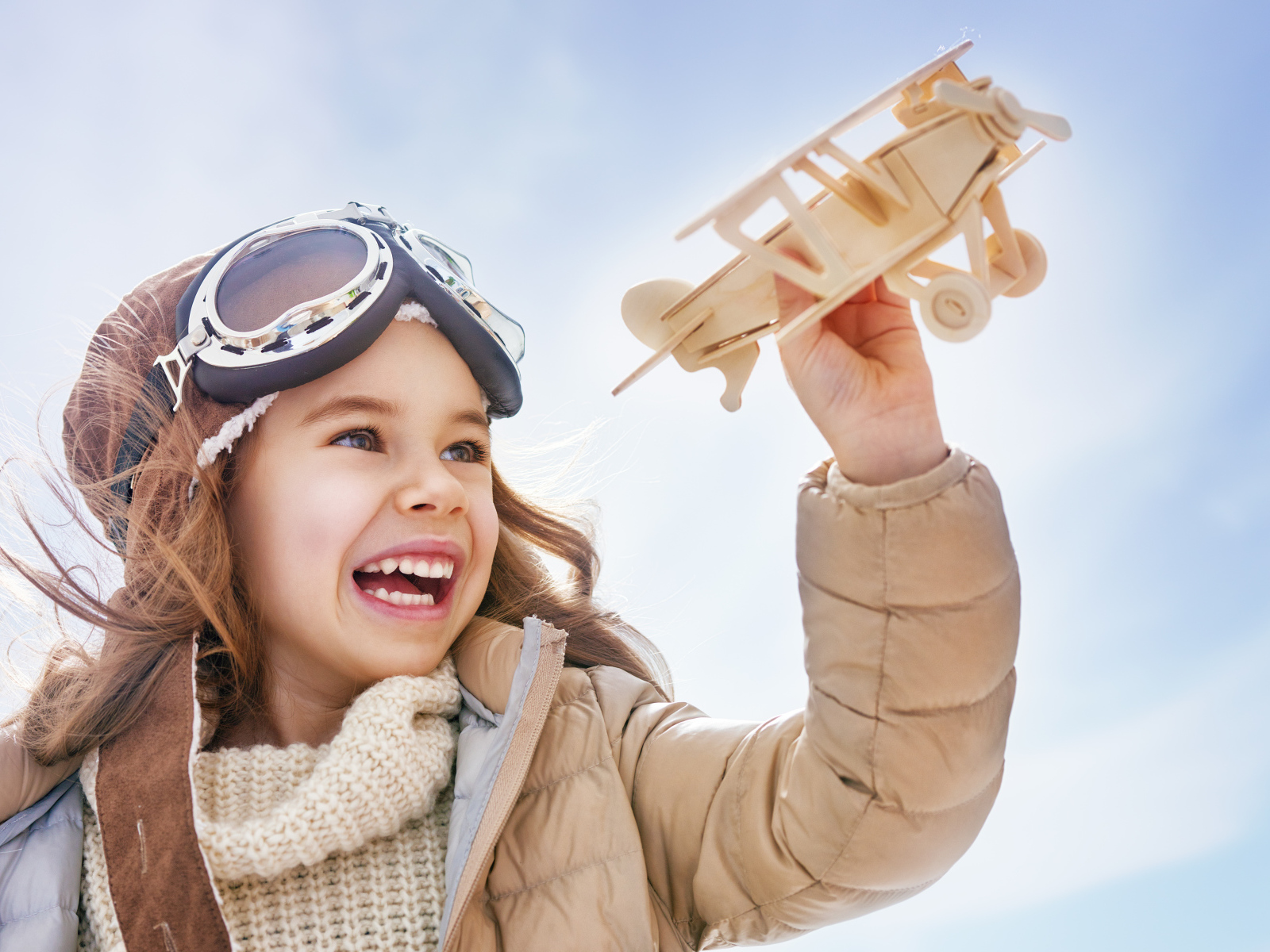 Маленькая улыбающаяся девочка с самолетом в руках 