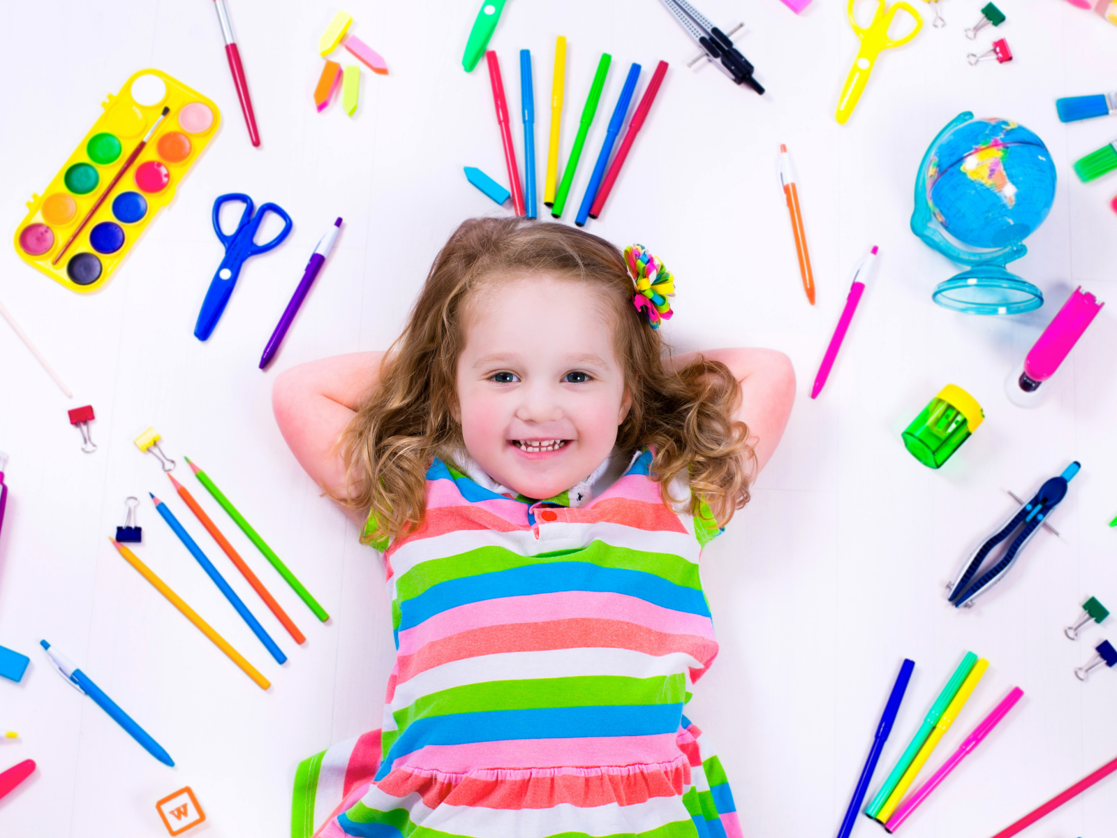 Маленькая улыбающаяся девочка со школьными принадлежностями