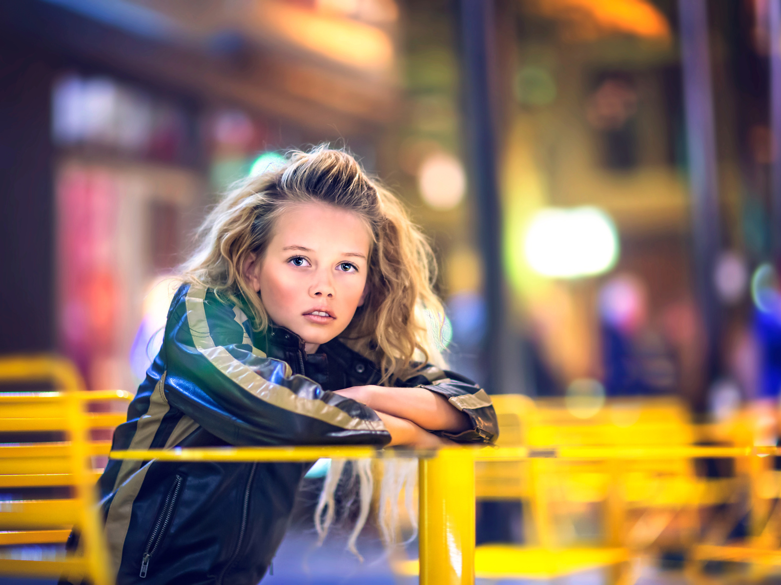 Длинноволосая девочка сидит на карусели