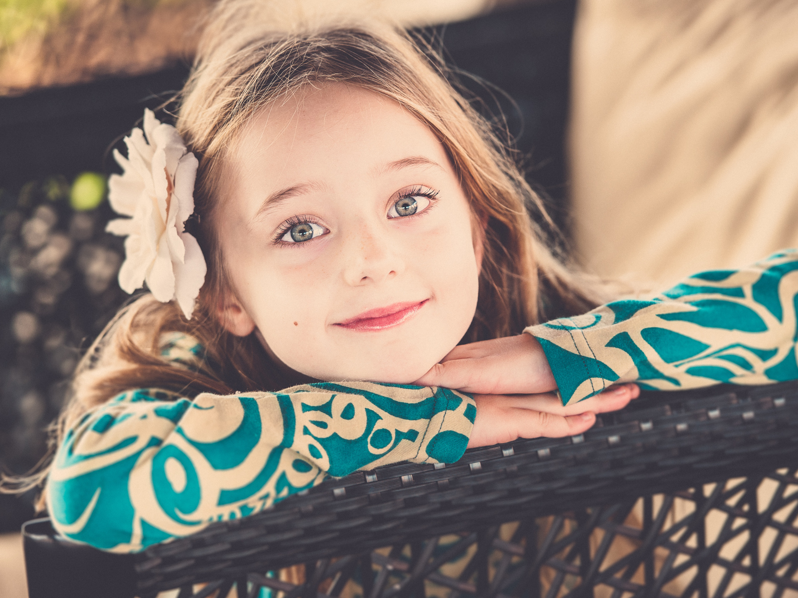 Улыбающаяся зеленоглазая девочка с белым цветком в волосах