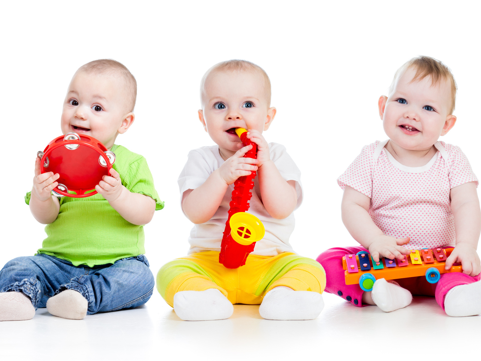 Three smiling babies playing against a white background