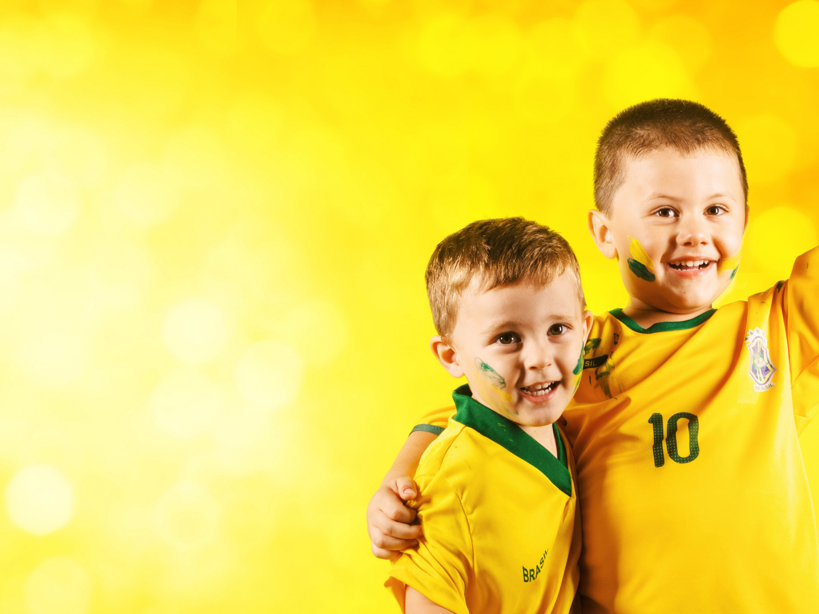 Два маленьких мальчика в спортивной форме на желтом фоне