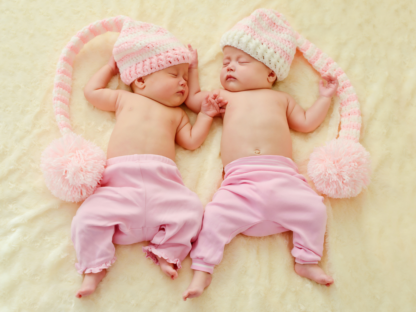 Два спящих грудных ребенка в розовых костюмах