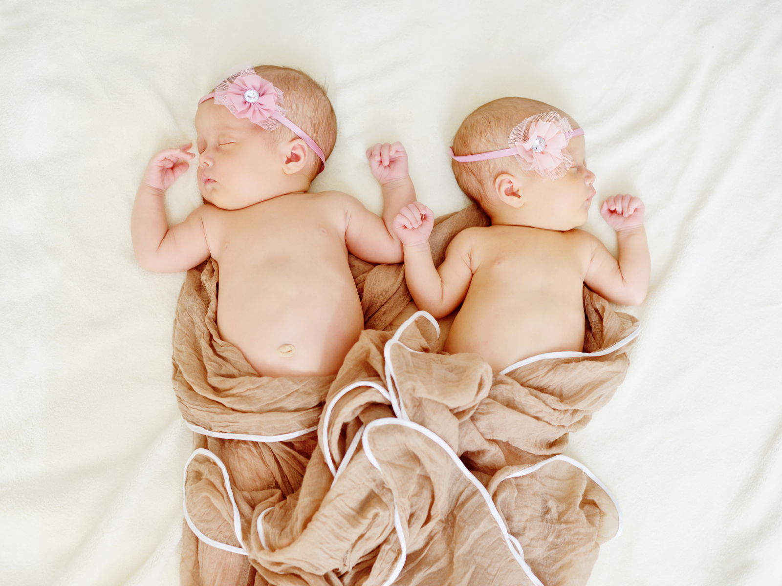 Два спящих младенца с розовыми цветами на голове