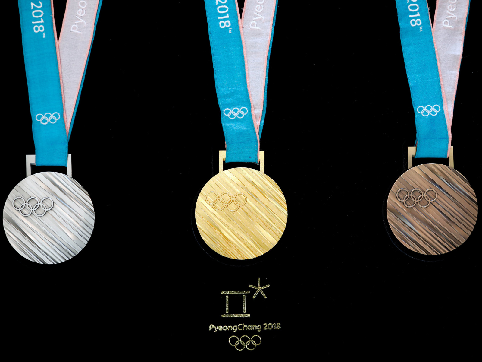 Три медали зимних Олимпийских игр 2018 на черном фоне