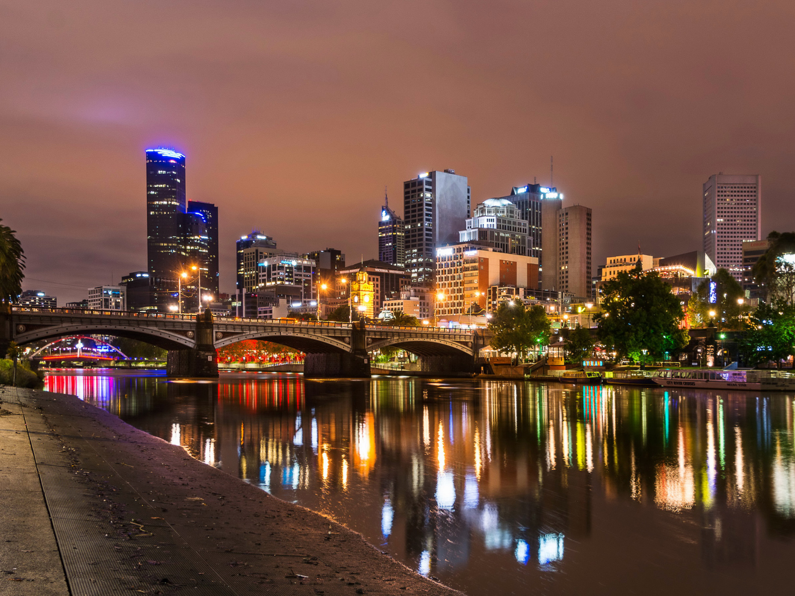 The lights of the night skyscrapers of the city of Melbourne are reflected in the water channel. Australia