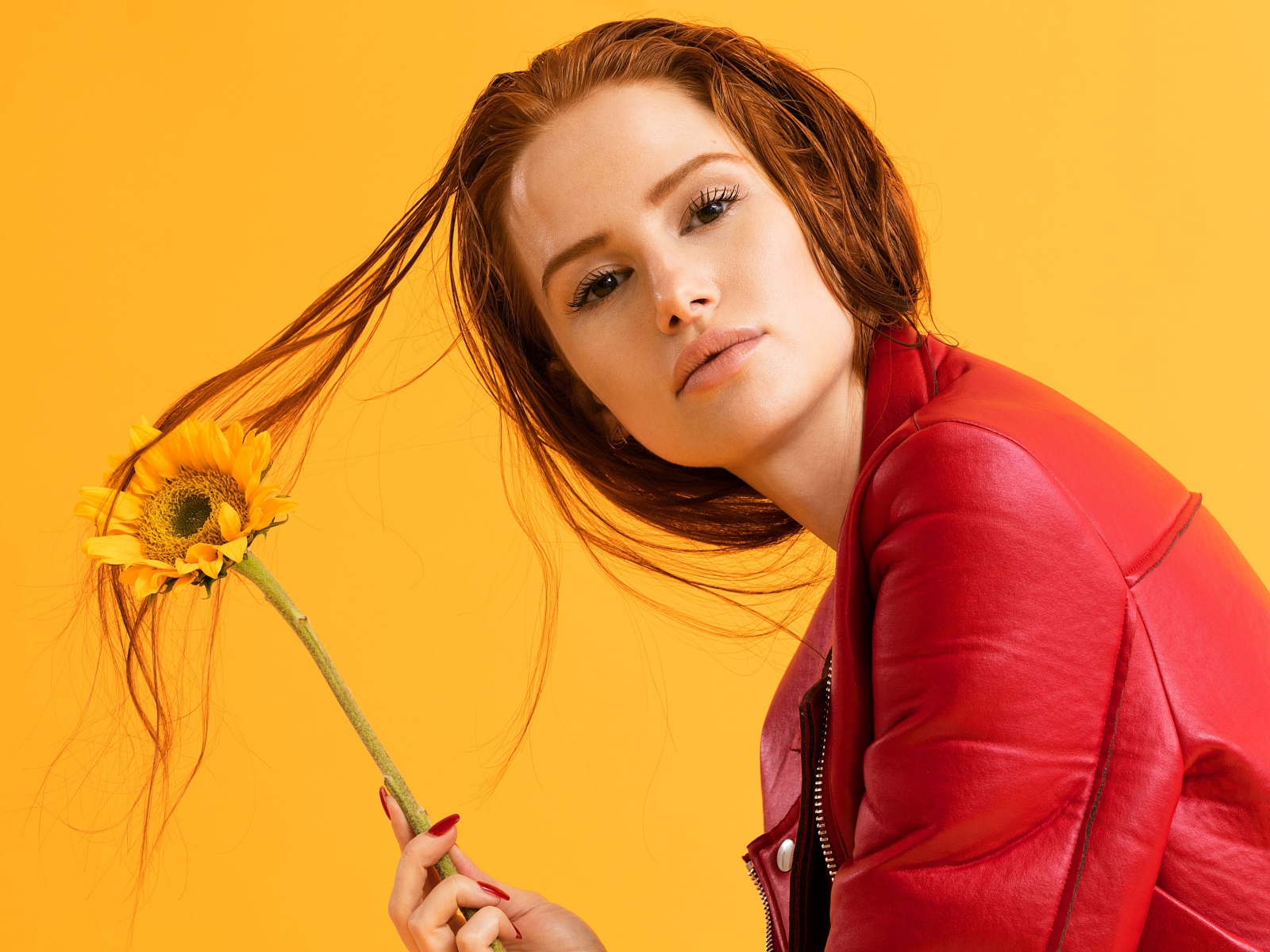 Актриса Мэделин Петш в красной куртке фото на оранжевом фоне