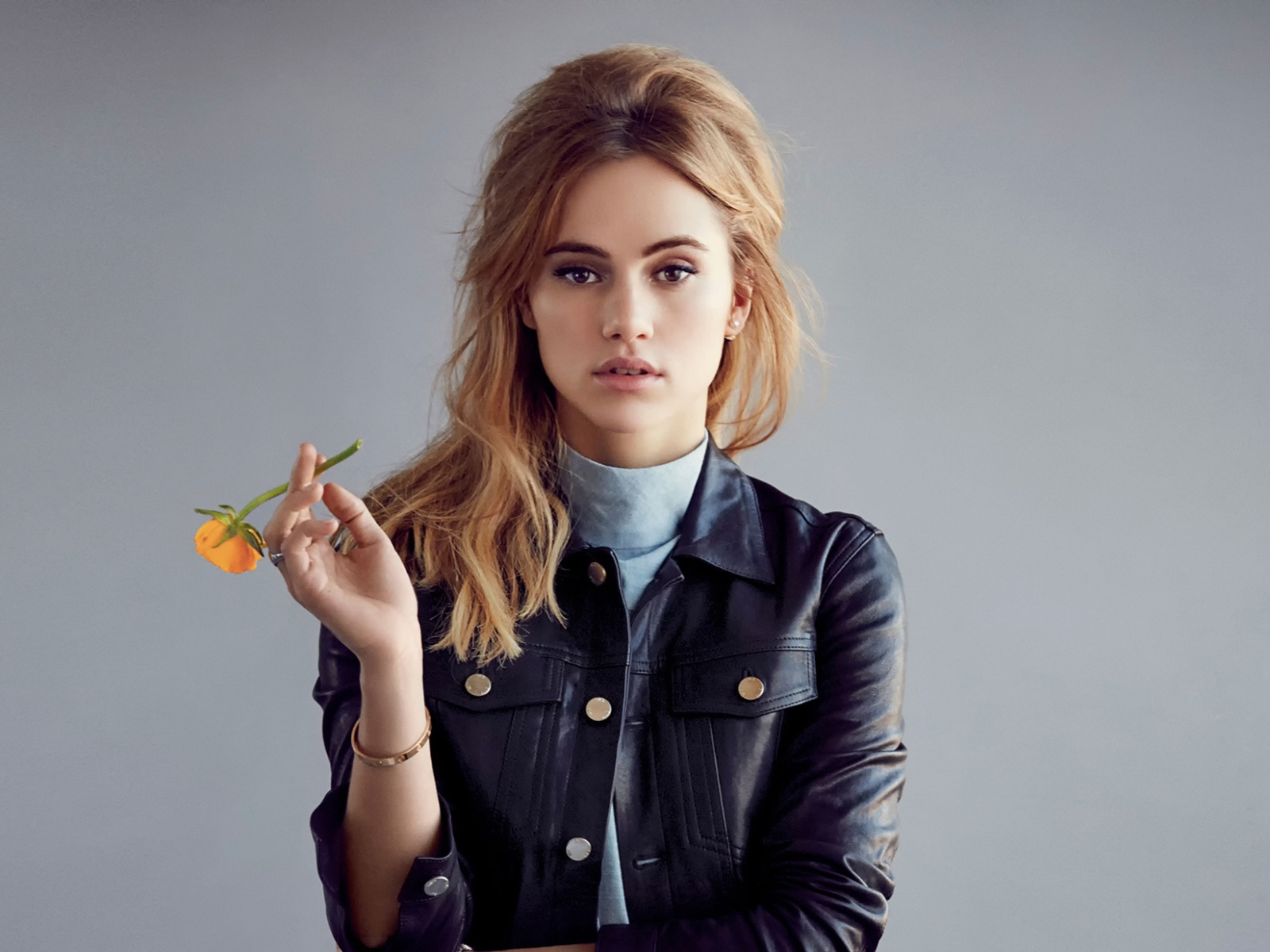 Актриса Сьюки Уотерхаус с цветком в руках на сером фоне
