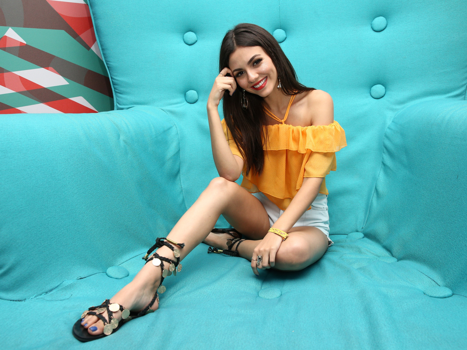 Актриса брюнетка Виктория Джастис сидит на синем диване 