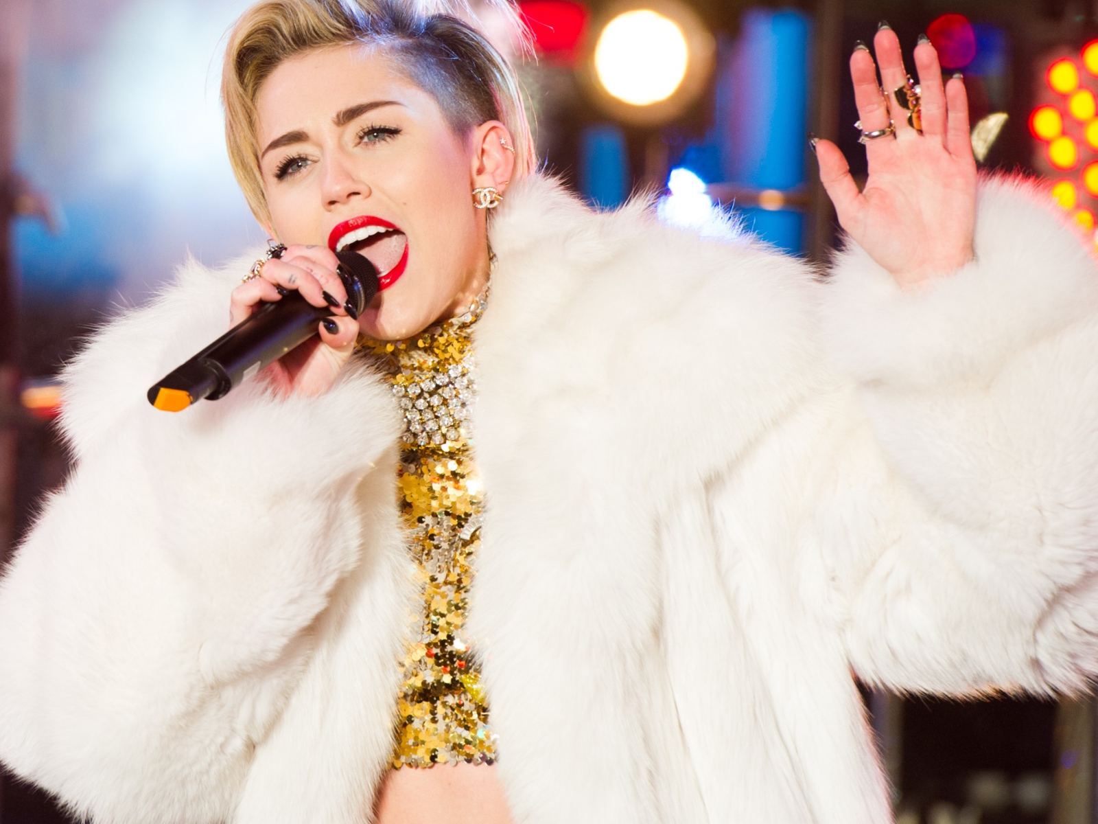 Popular young singer Miley Cyrus in a white fur coat on stage